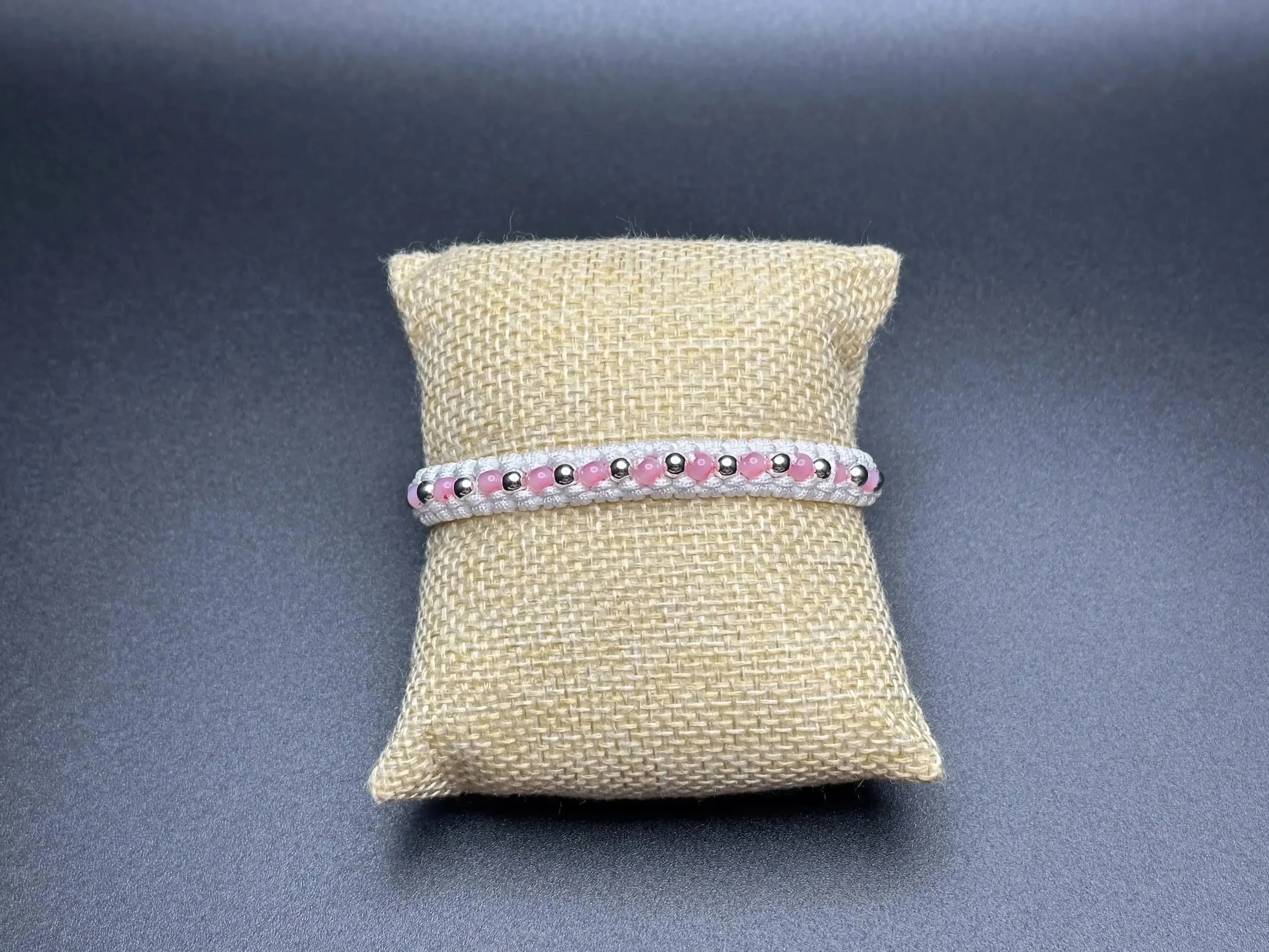 an airy and romantic hand-woven anchor bracelet designed with a signature white macramé pattern and sterling silver beads.