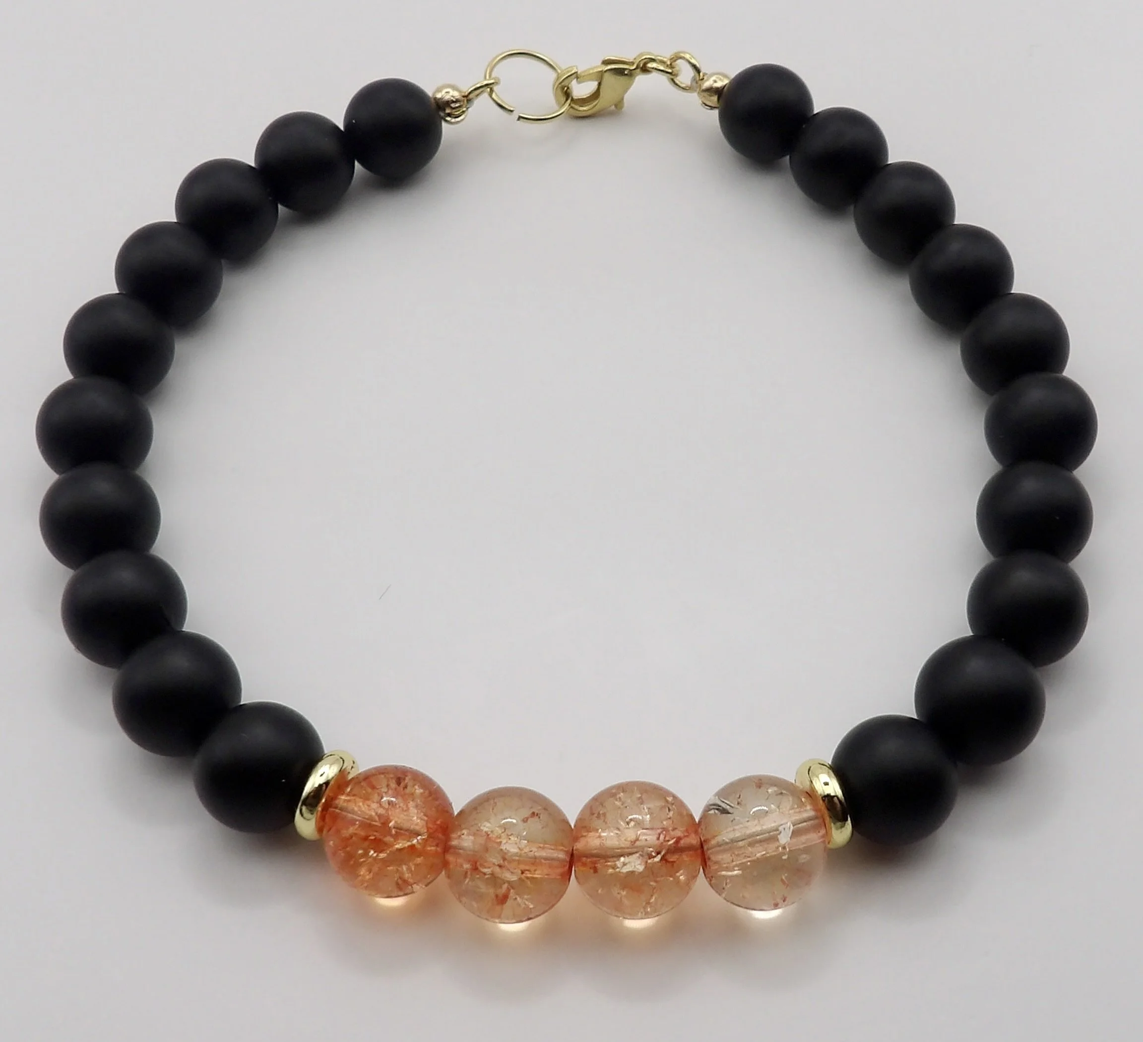 close-up detail of the peachy-pink crackle quartz beads and 18k solid gold heishi spacers on the onyx bracelet.