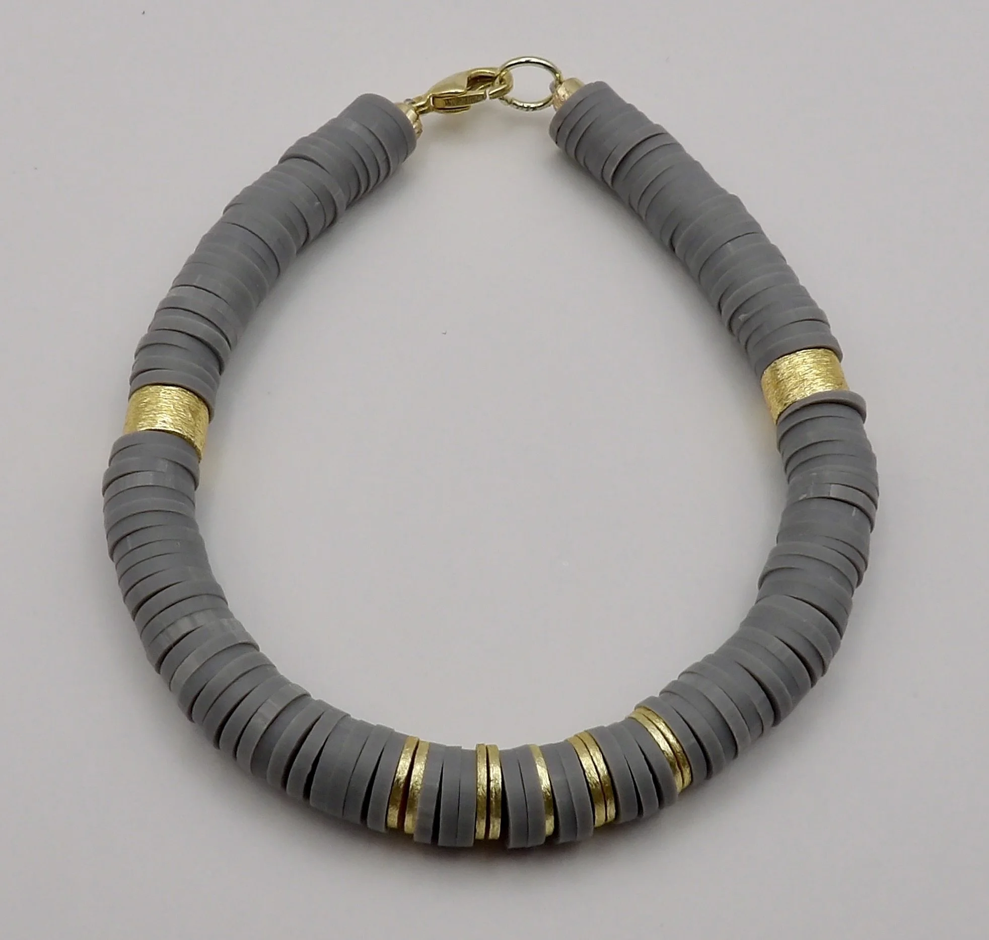 handmade 14k solid gold and gray polymer clay heishi bracelet, featuring a unique symmetrical pattern of brushed gold beads and a 14k gold clasp.