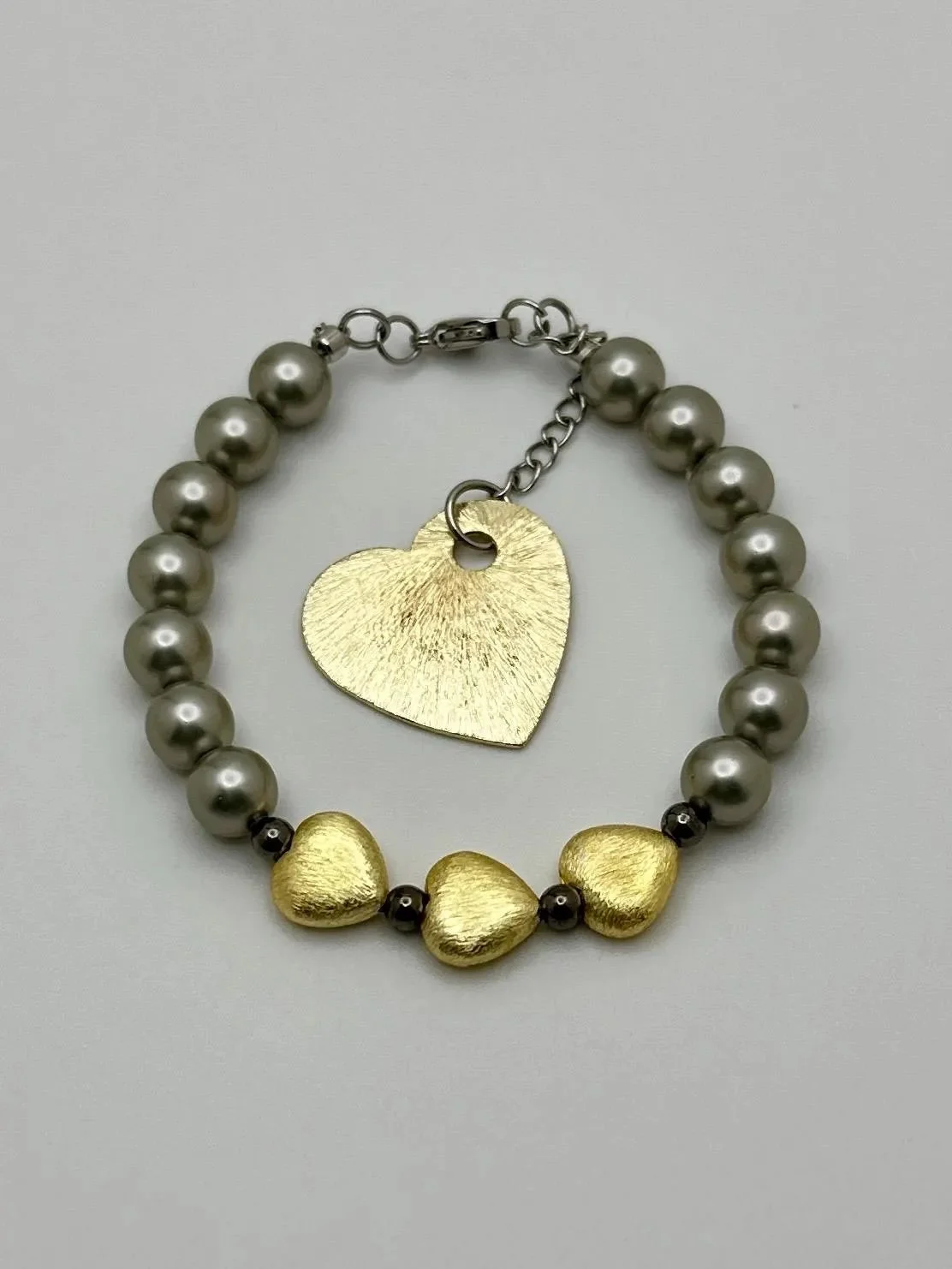 mixed-metal heart bracelet featuring a combination of warm brushed gold, dark gunmetal, and silver-tone hematite.