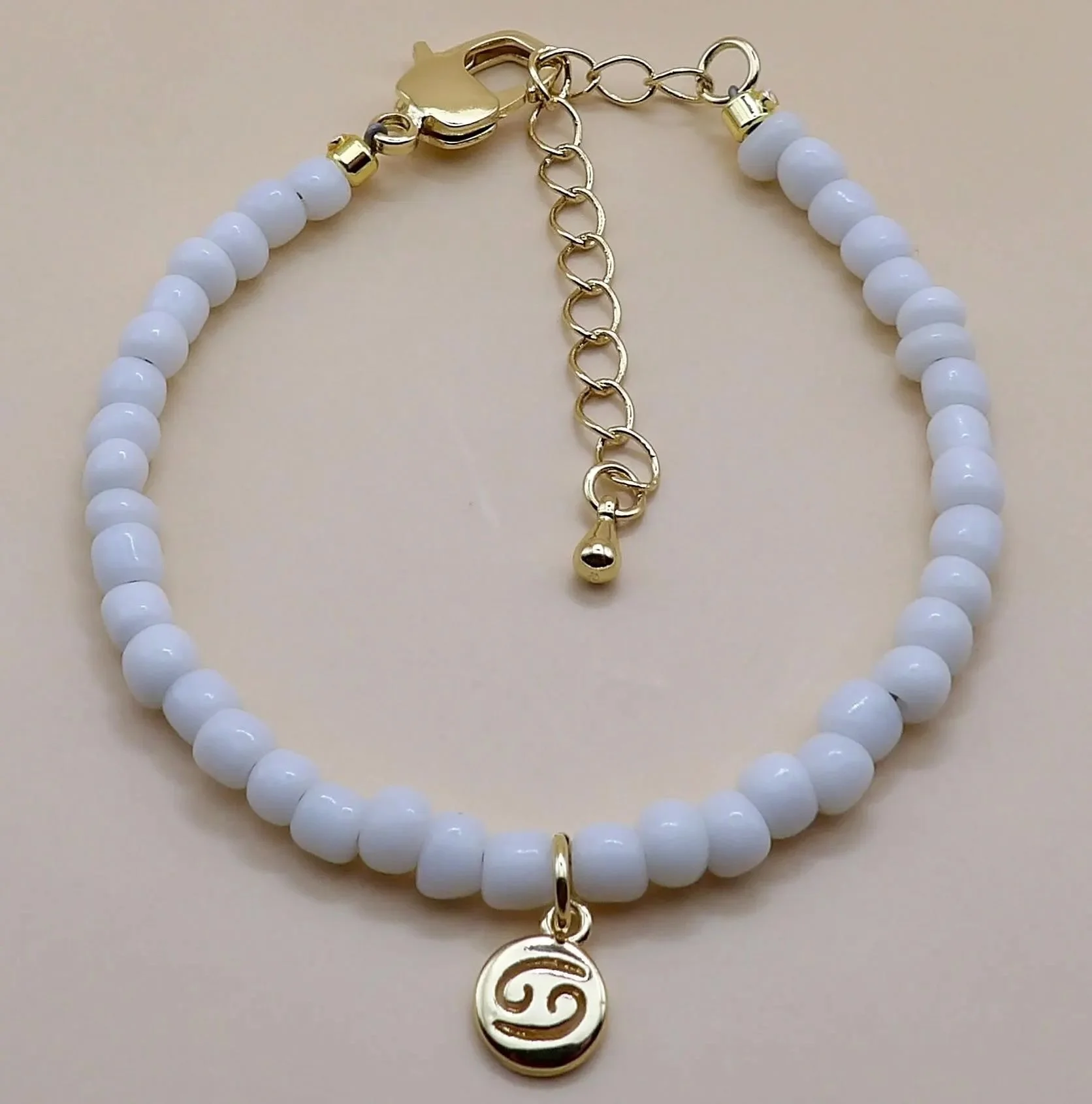 dainty 18k gold plated zodiac jewelry with white beads, reflecting a modern, "clean girl" aesthetic.