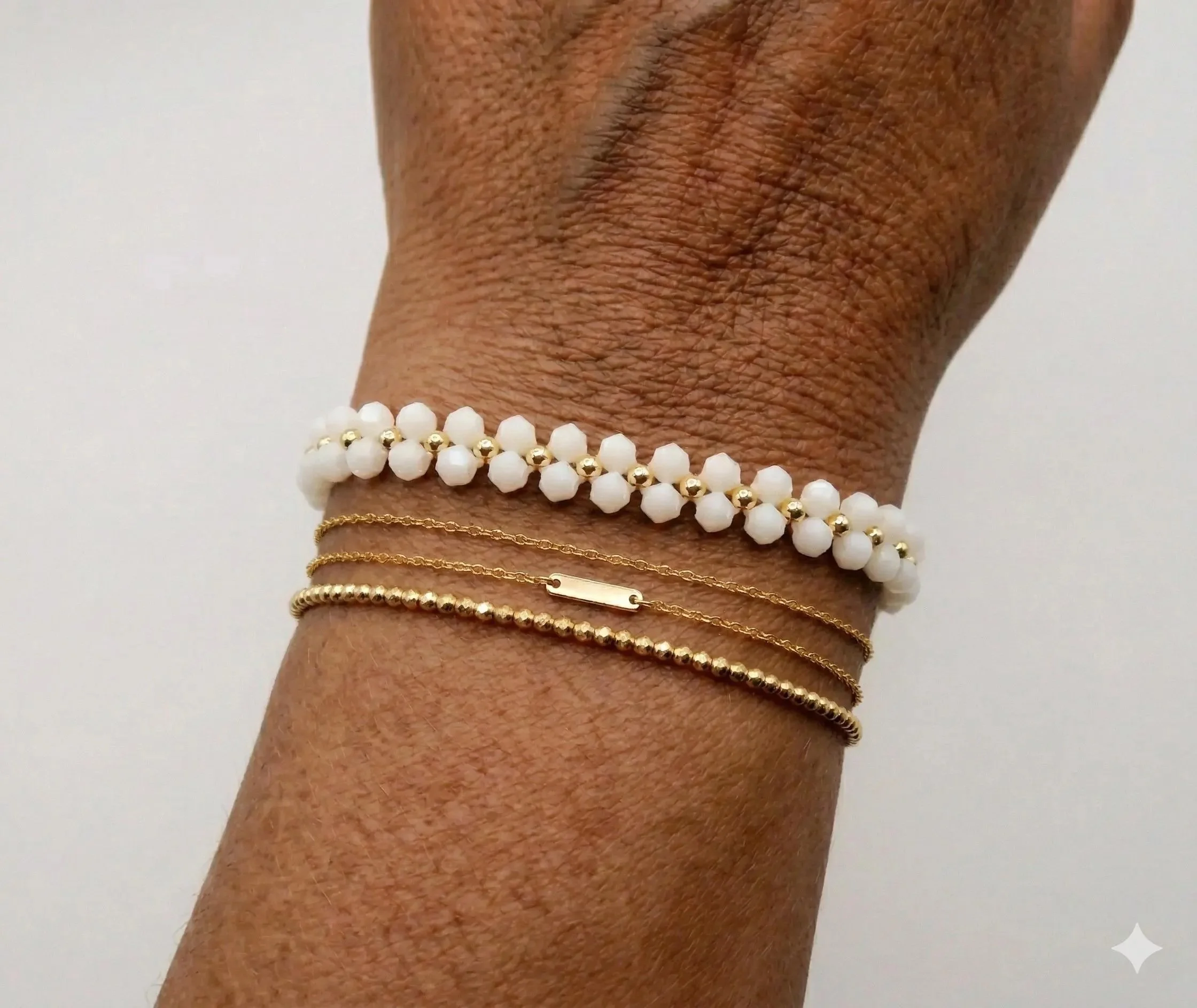 Close-up of a white bicone crystal bloom bracelet highlighting the precision of the woven daisy chain and metallic gold centers.