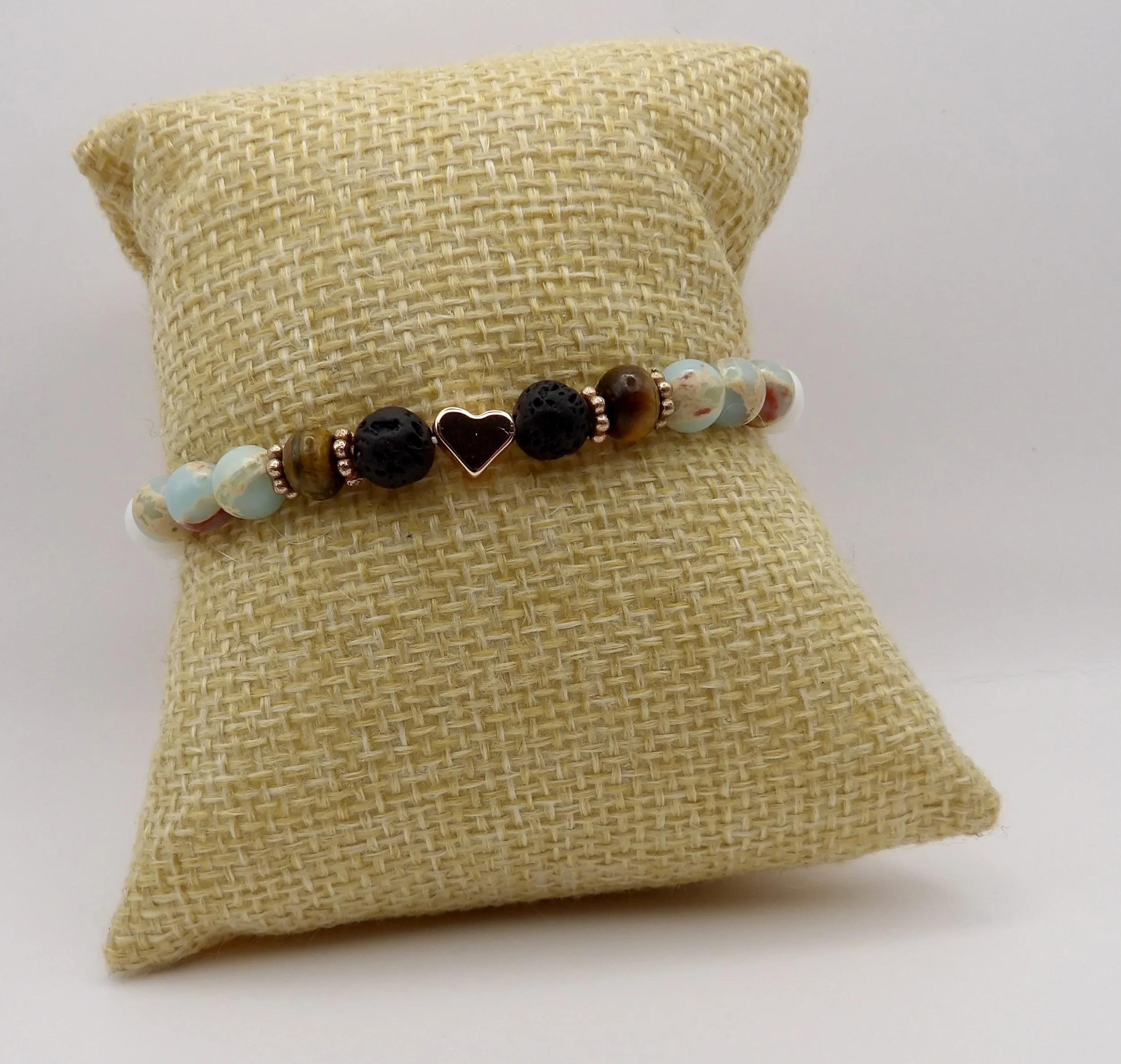 view of the smooth matte white jade beads comprising the back half of the rose gold heart mixed gemstone bracelet.
