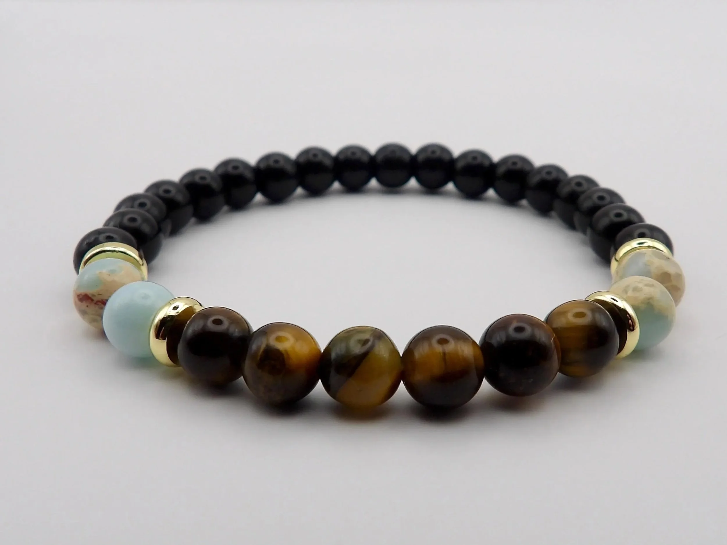 a high-contrast gemstone bracelet showing the warm tones of tiger's eye and the soft blues of african opal against sleek, polished black glass beads.
