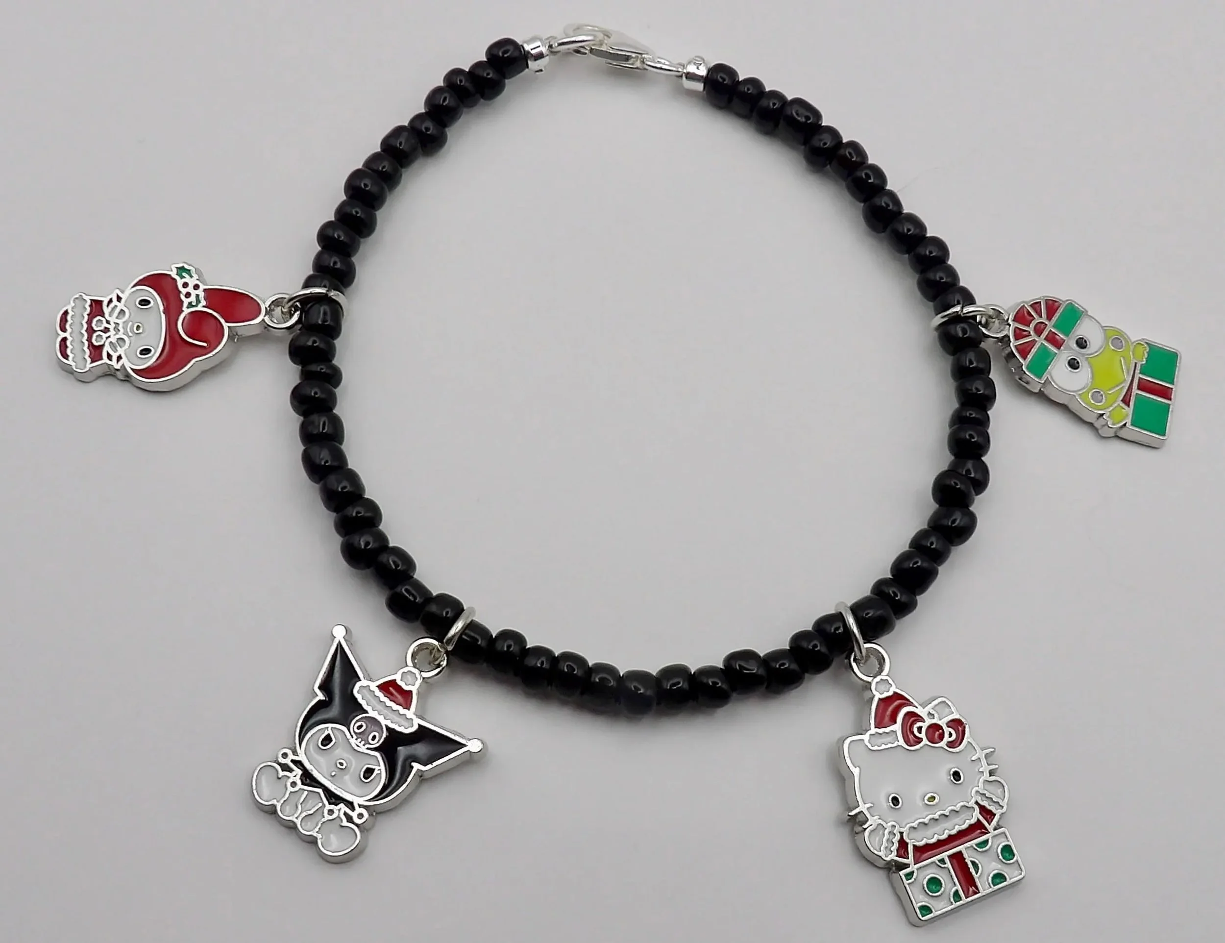 close-up of the kawaii holiday queen bracelet highlighting the sterling silver christmas charms and the sleek, dark aesthetic of the black beads.