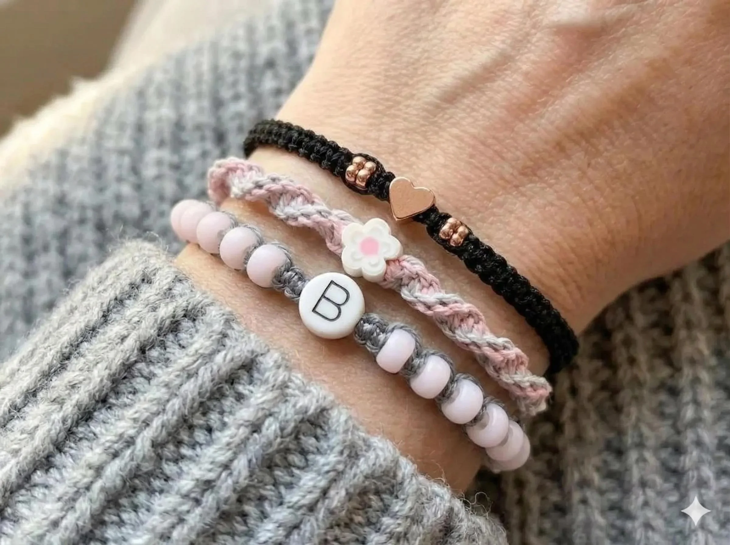 a curated jewelry trio showing a personalized initial bead and a shimmering rose gold heart on hand-woven cords.