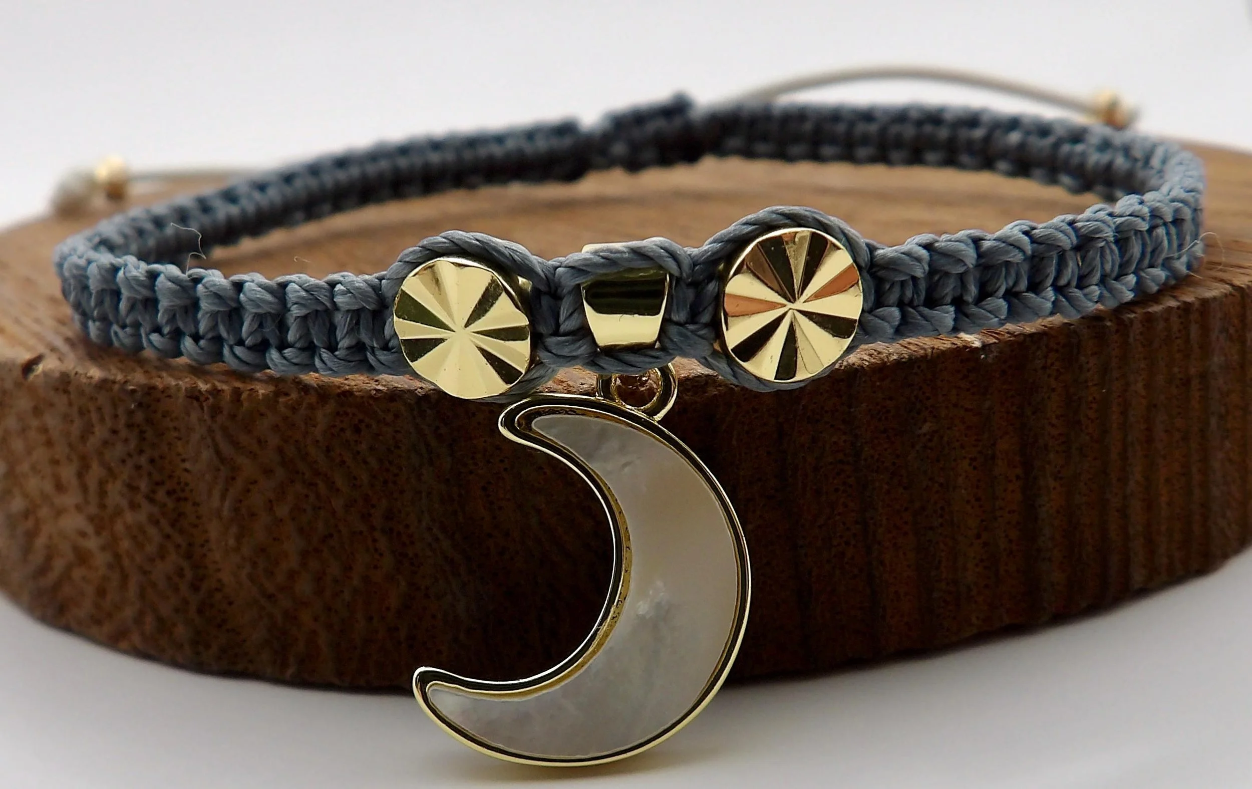 Celestial trendsetter jewelry featuring a gold moon and starburst design on a dark gray woven architectural base.