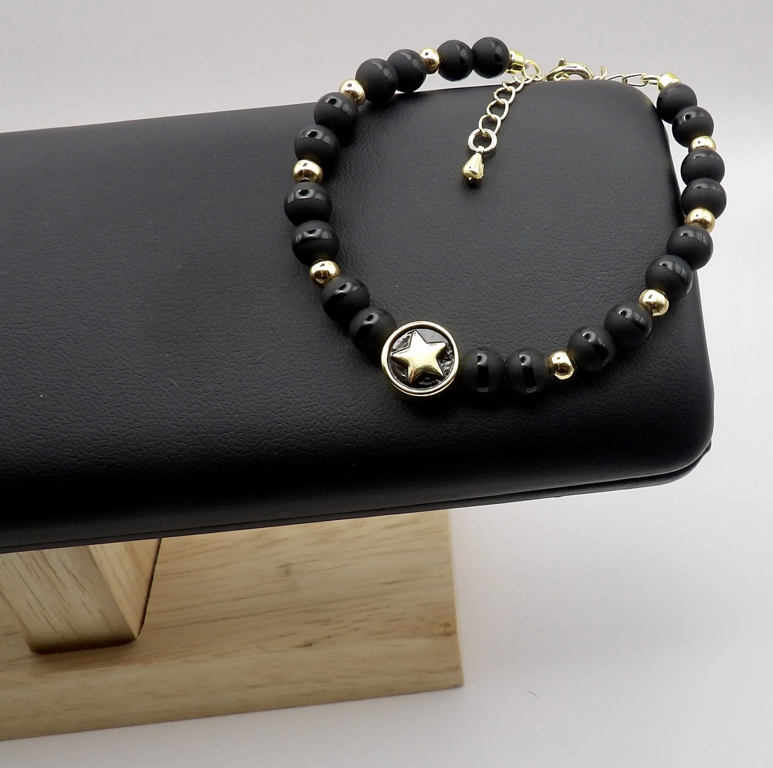 close-up detail of the 18k gold heart on black enamel spacer, contrasting with the matte and polished tuxedo onyx beads.