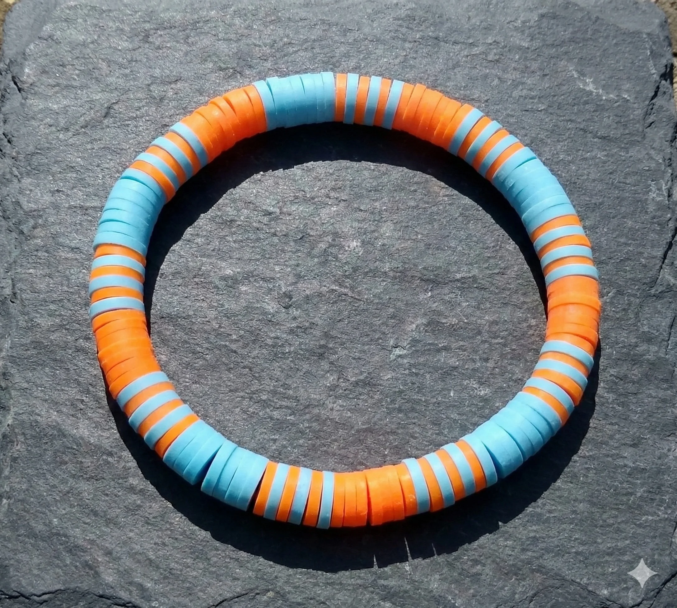 High-contrast orange and cool blue polymer clay heishi bracelet in a bold color-block design.