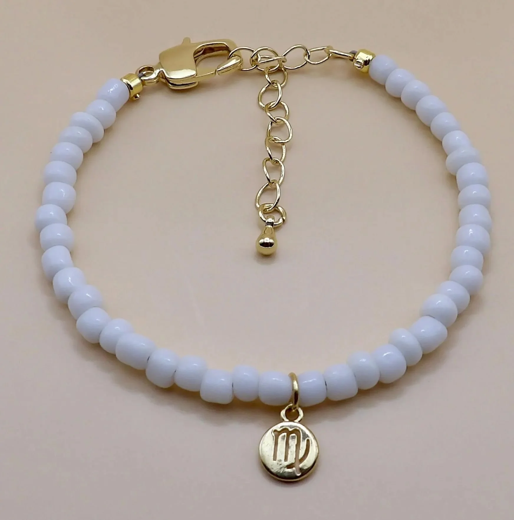 astrology charm bracelet in gold and white, featuring an adjustable sliding knot for a custom fit.