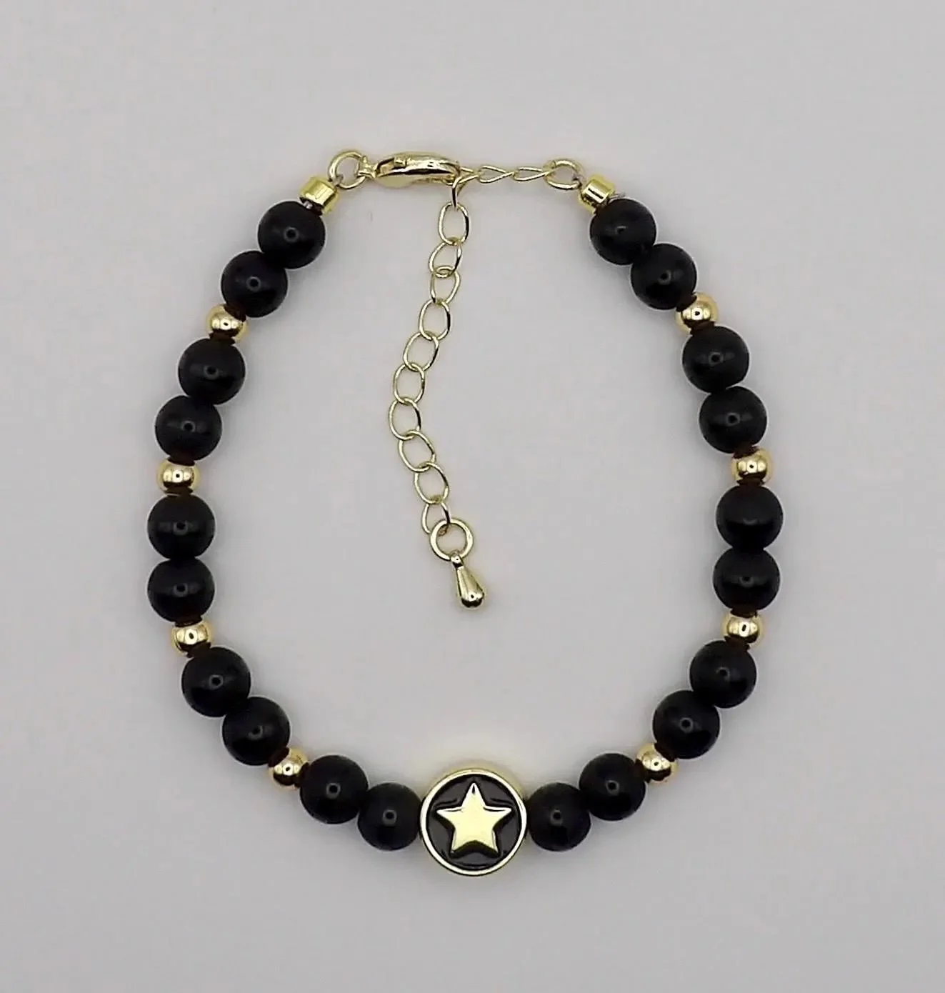 an elegant "corporate goth" anchor bracelet designed for daily wear, balancing deep black minerals with high-shine gold celestial hardware.