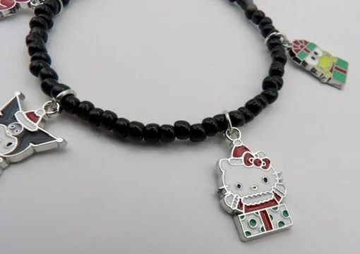 handmade 925 sterling silver christmas charm bracelet with 4 sanrio character charms (hello kitty, kuromi, my melody, keroppi) on a 3mm black glass bead band.
