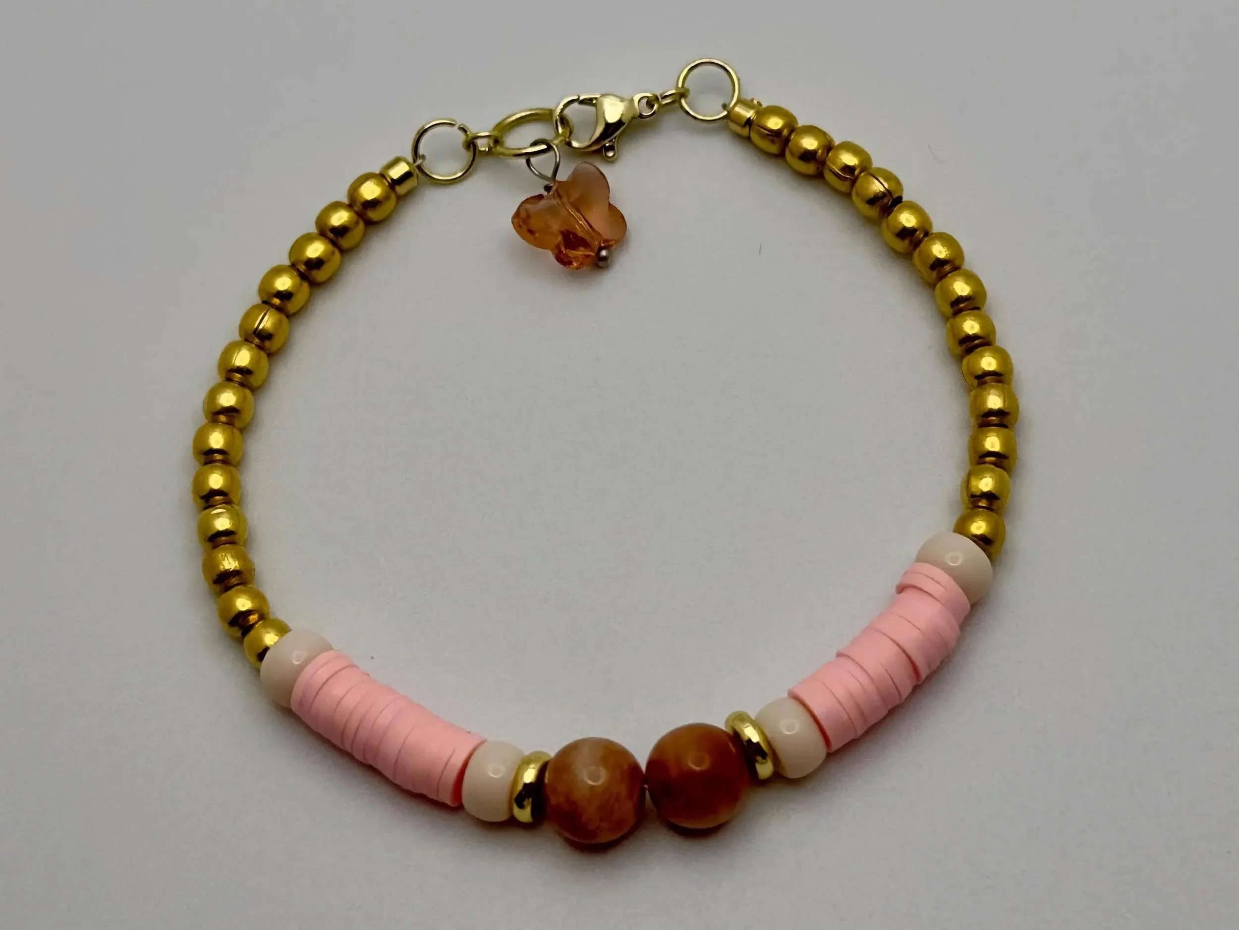 feminine stacking bracelets featuring 18k gold-finished hardware and a butterfly charm representing transformation.