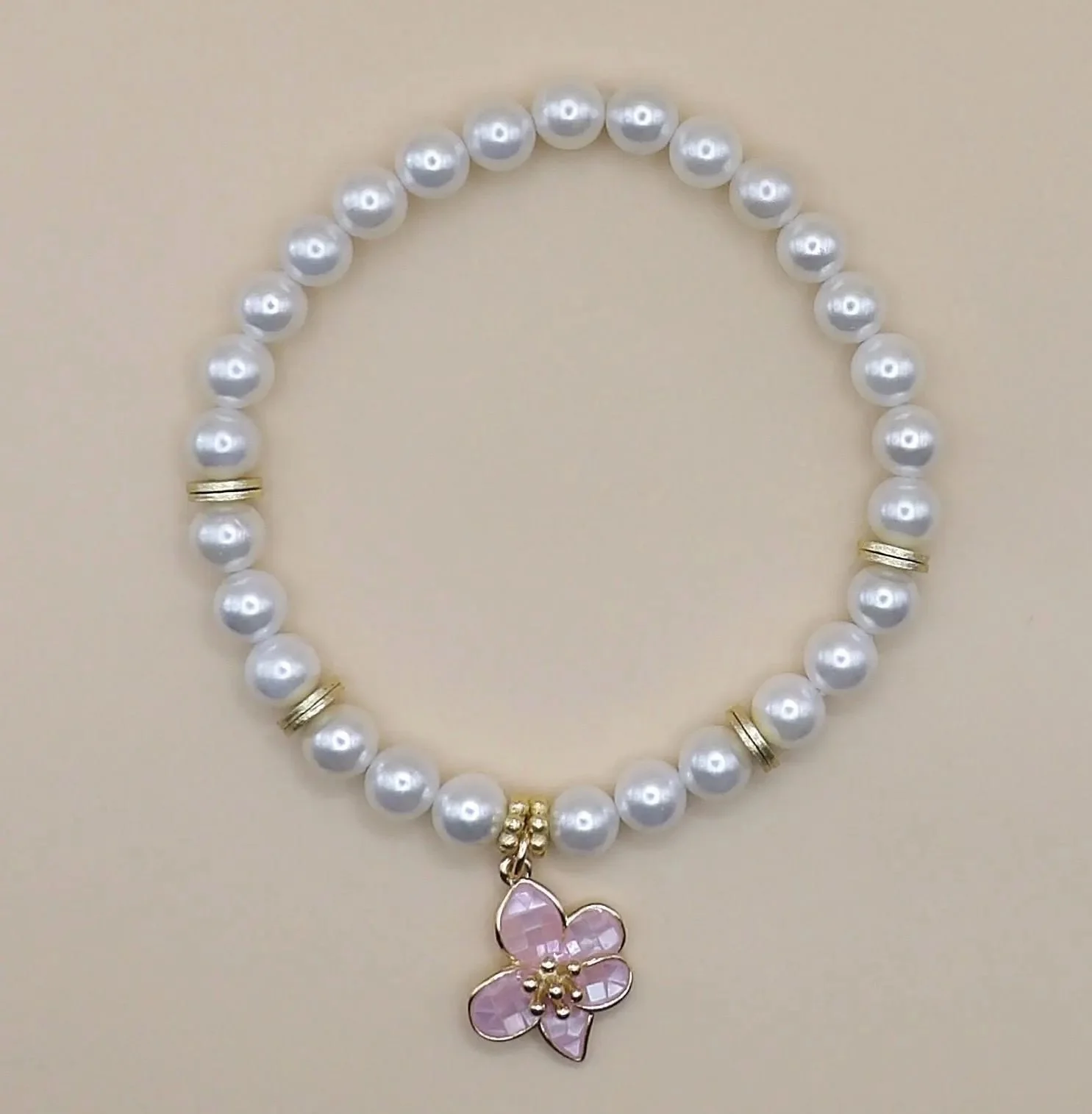 a minimalist stacking bracelet featuring iridescent pearls and a rhythmic 18k gold flower centerpiece for a romantic look.