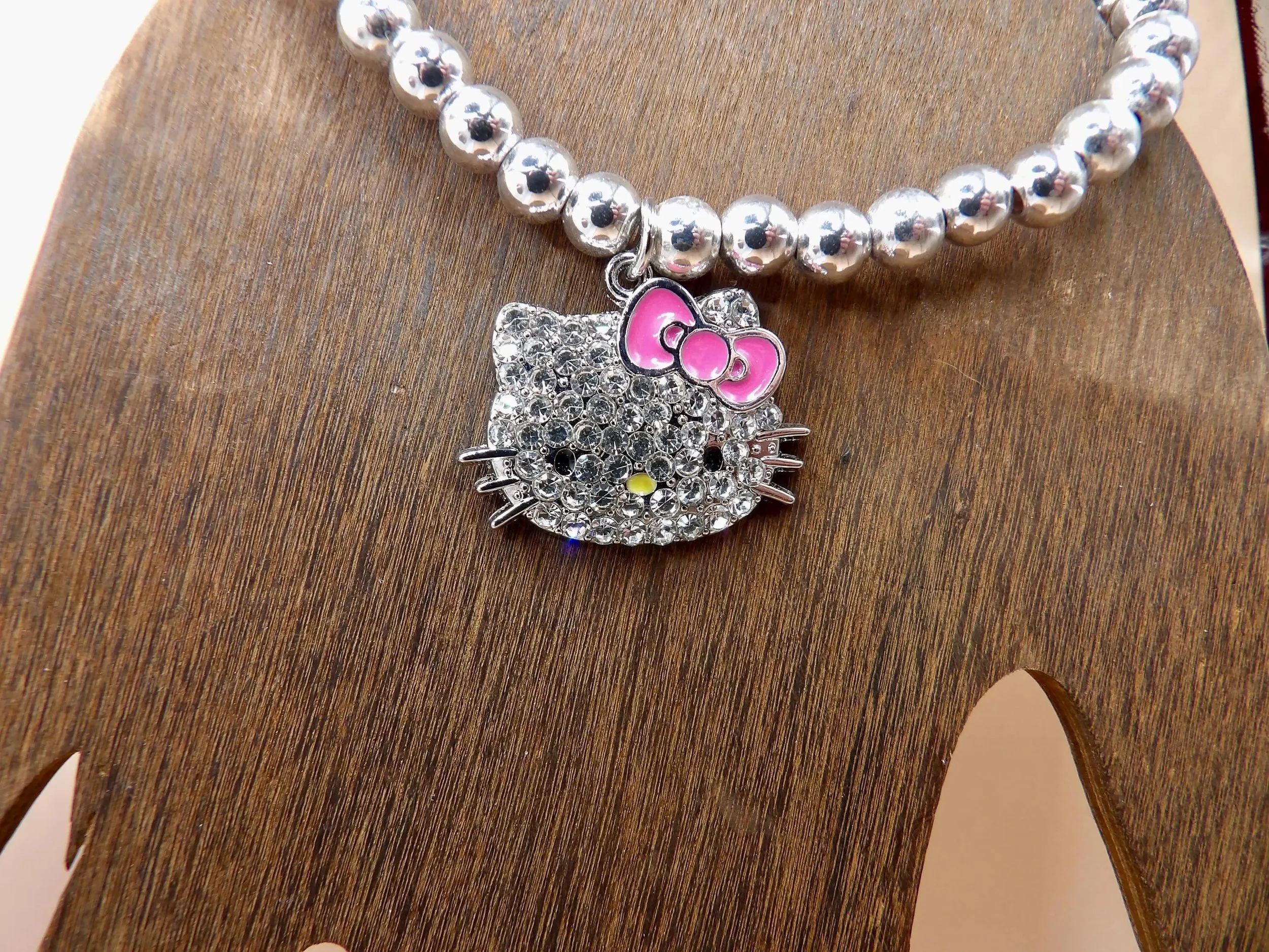 a durable, heirloom-quality hello kitty bracelet handcrafted with genuine .925 silver and a pink mosaic collectors charm.