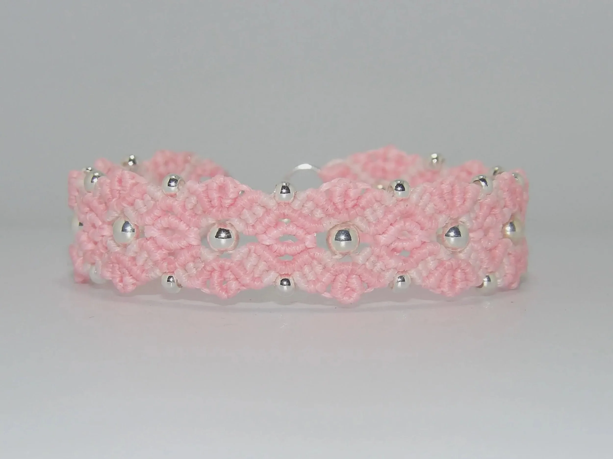 detailed view of the .925 sterling silver components integrated into the hand-knotted light pink floral weave.