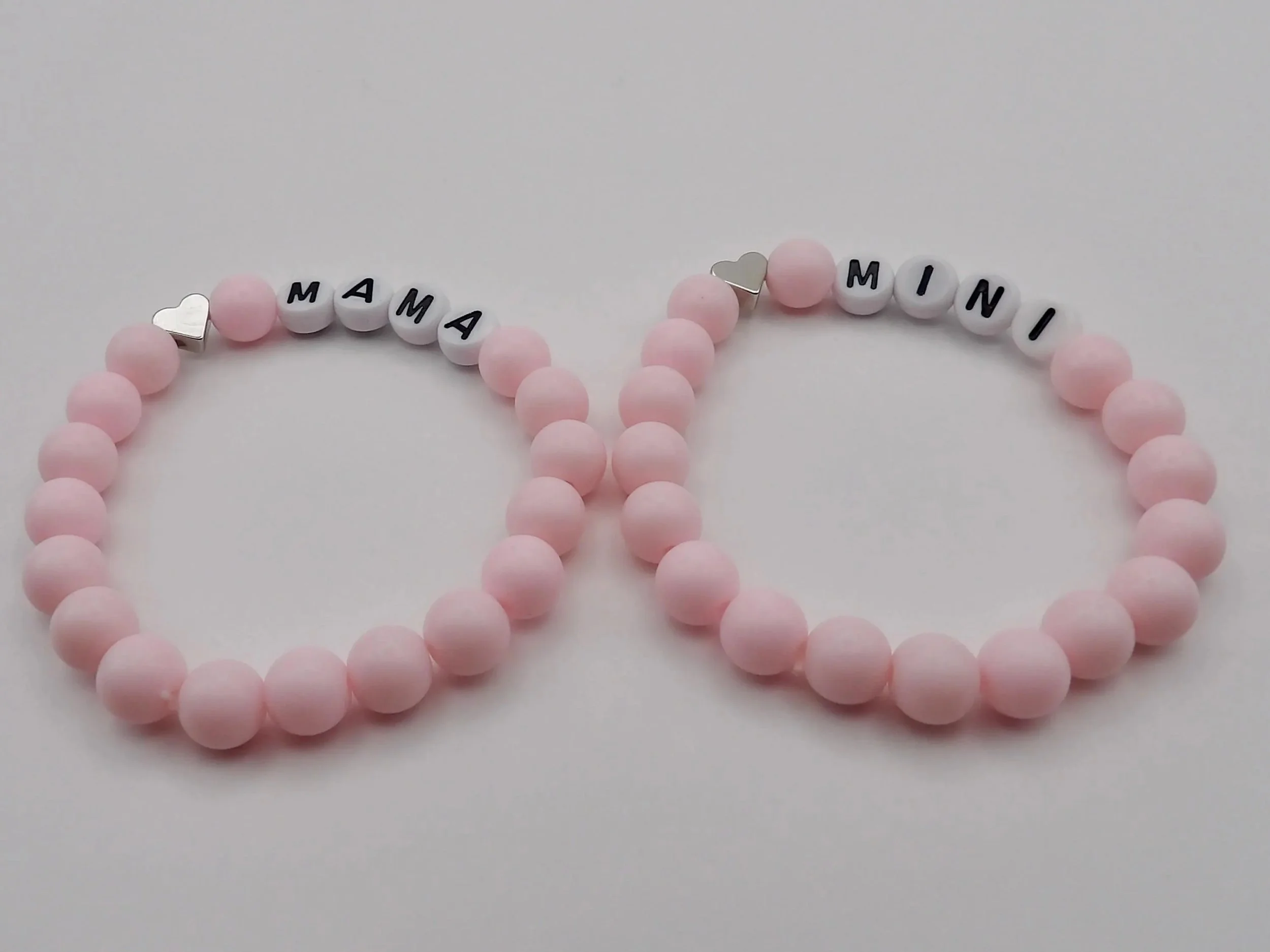 detailed view of the .925 sterling silver hallmark on the mama and mini matching heart charms with iridescent pink accents.
