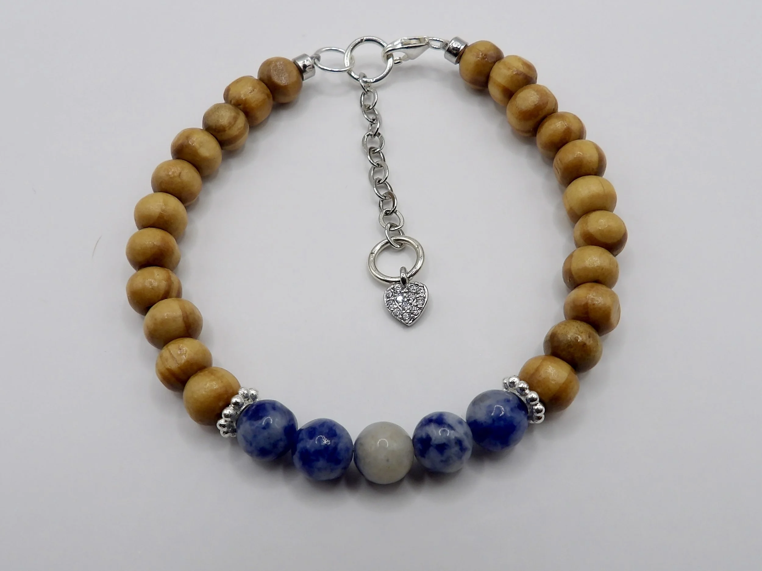 person wearing the delicate blue sodalite and brown wood bead bracelet, showing its minimalist style and pave heart charm.