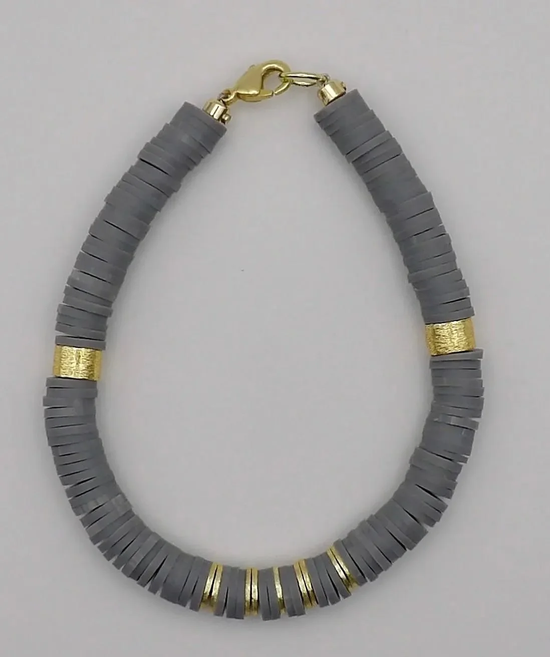 handcrafted architectural-style jewelry with a rhythmic pattern of gray beads and high-quality brushed gold hardware.