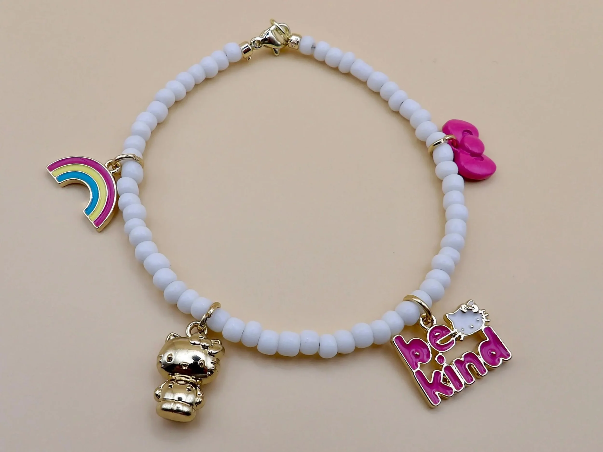 the cheerful collector bracelet featuring a polished 18k gold-plated hello kitty charm centered on a strand of crisp white seed beads.