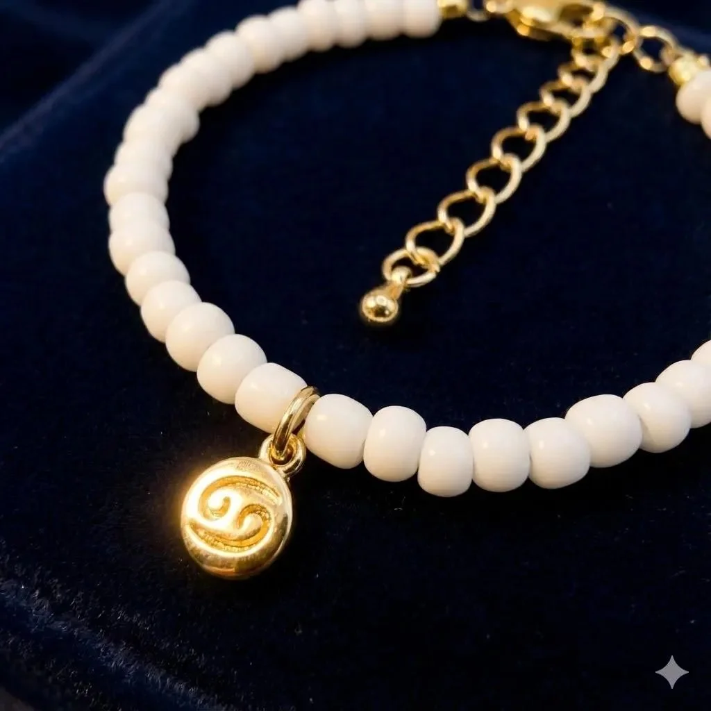 close-up of a shimmering gold zodiac charm on a strand of uniform white seed beads with a gold-filled clasp.