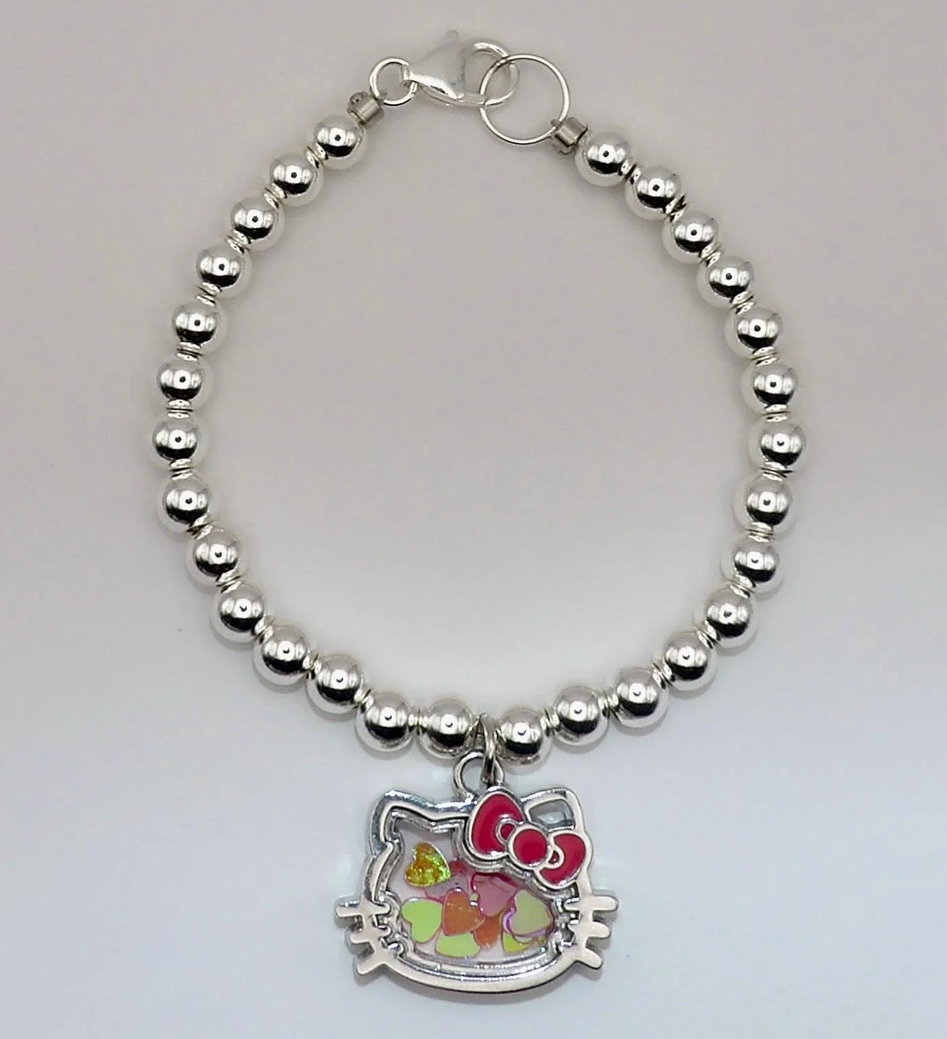 close-up of the hello kitty shaker bracelet highlighting the precision-strung silver beads and the movement of the shaker charm.