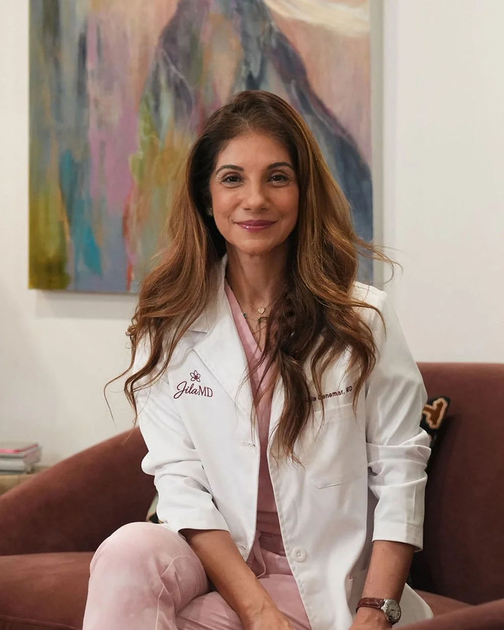 Dr. Jila Senemar sitting in her office on a maroon sofa