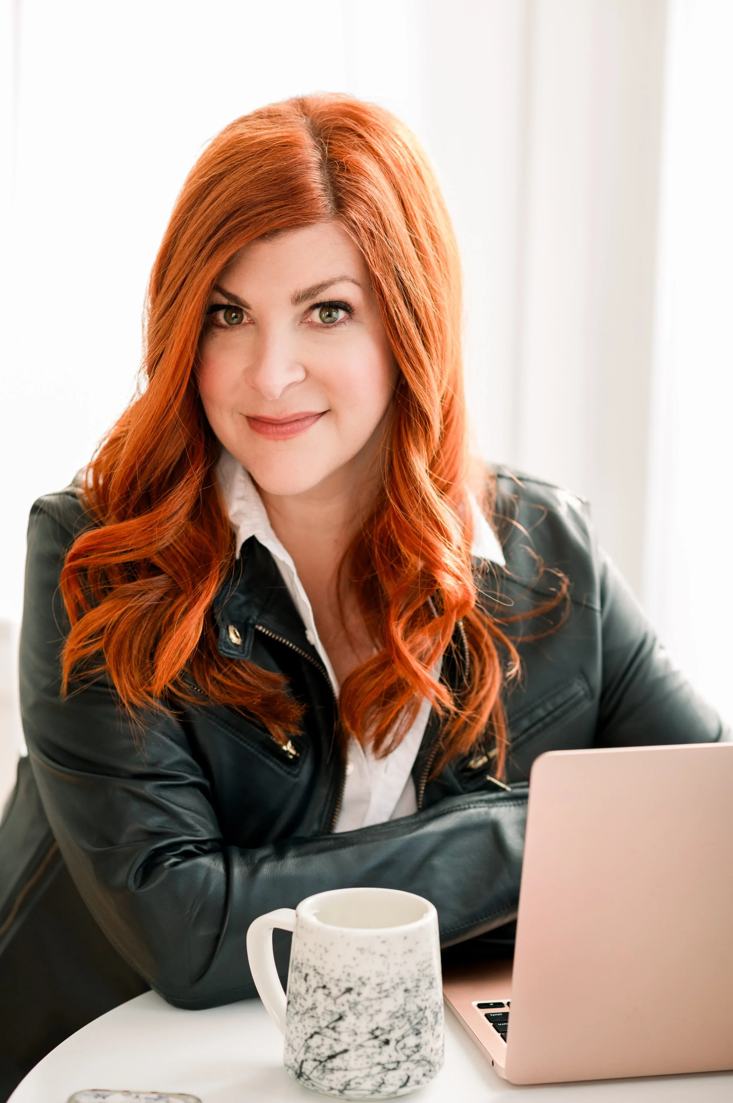 Kacy Fleming sitting at a table with a coffee mug and her laptop open