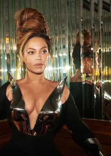 A woman with an elaborate hairstyle and shiny metallic outfit sitting in front of a mirror.