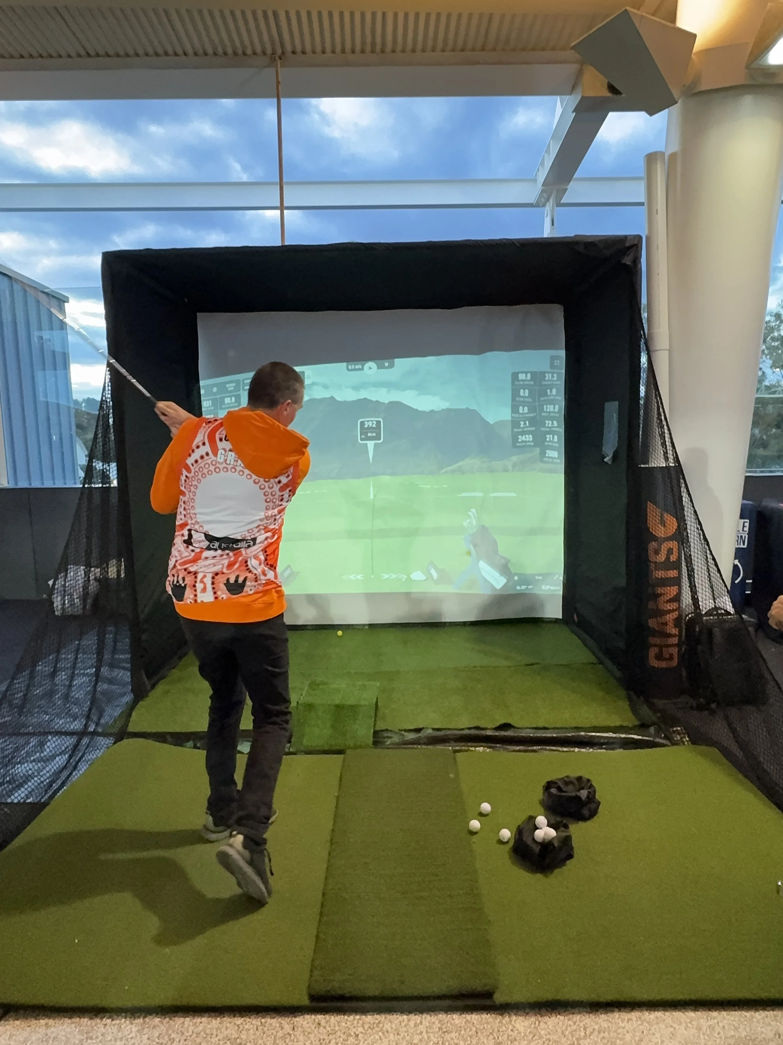 GWS Giants participant taking a swing on a golf simulator