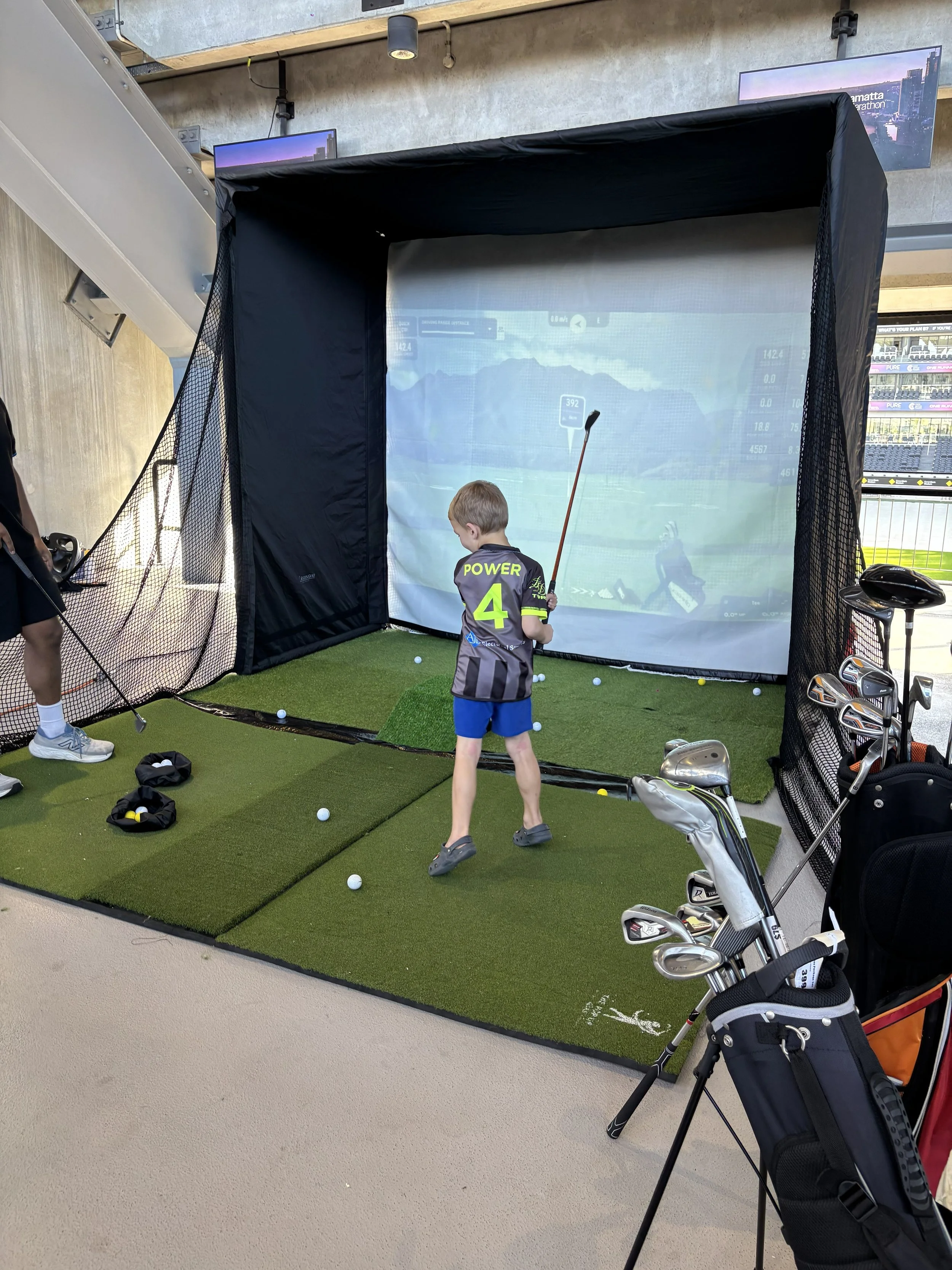 Event host coaching a first-time golfer on a portable golf simulator