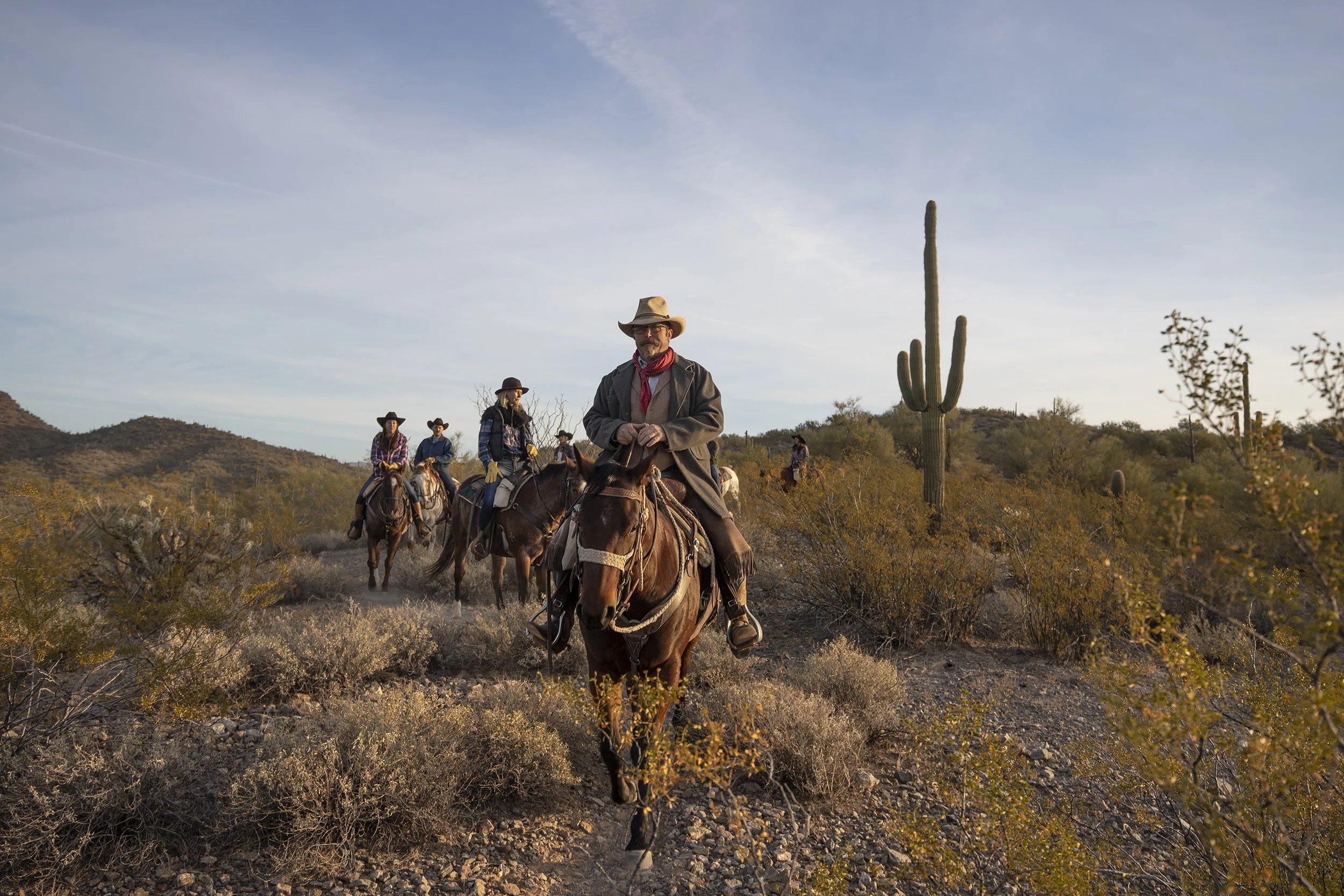 Dude ranch guests riding horses through the Arizona desert.
