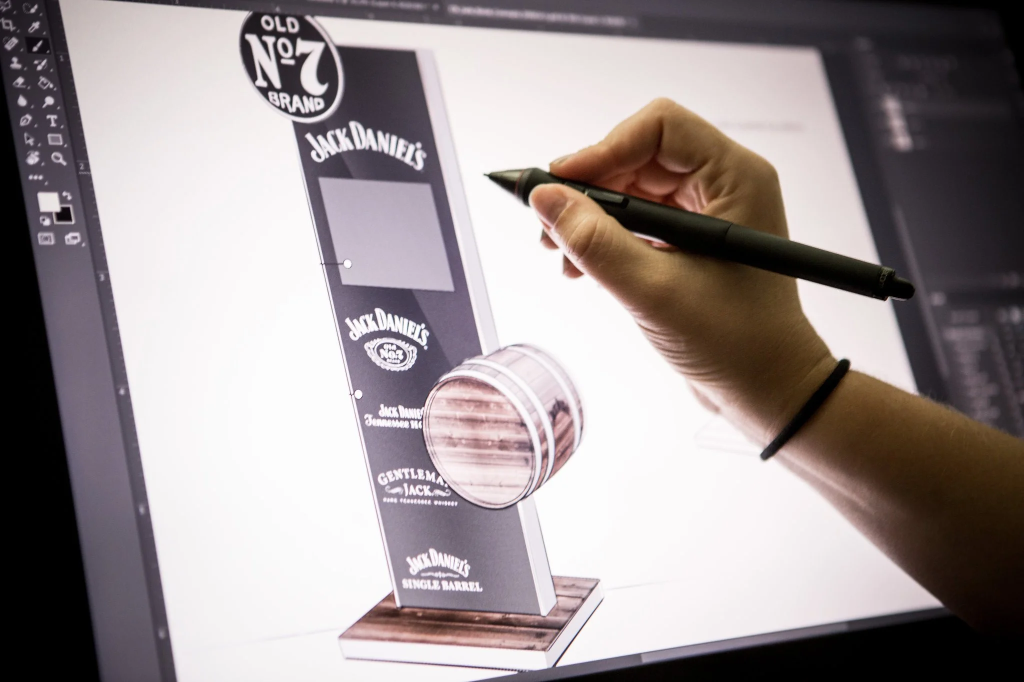 A person designing a Jack Daniel's whiskey display on a digital drawing tablet.
