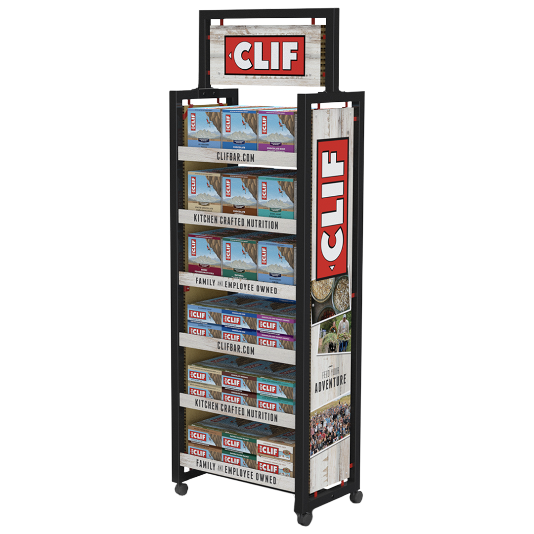 A display rack filled with various packages of Clif Bar energy bars, with the Clif logo at the top and on the individual packages. The rack also has signage promoting Clif Bar's website and message about family and employee ownership, along with scenic images and adventure-themed slogans.