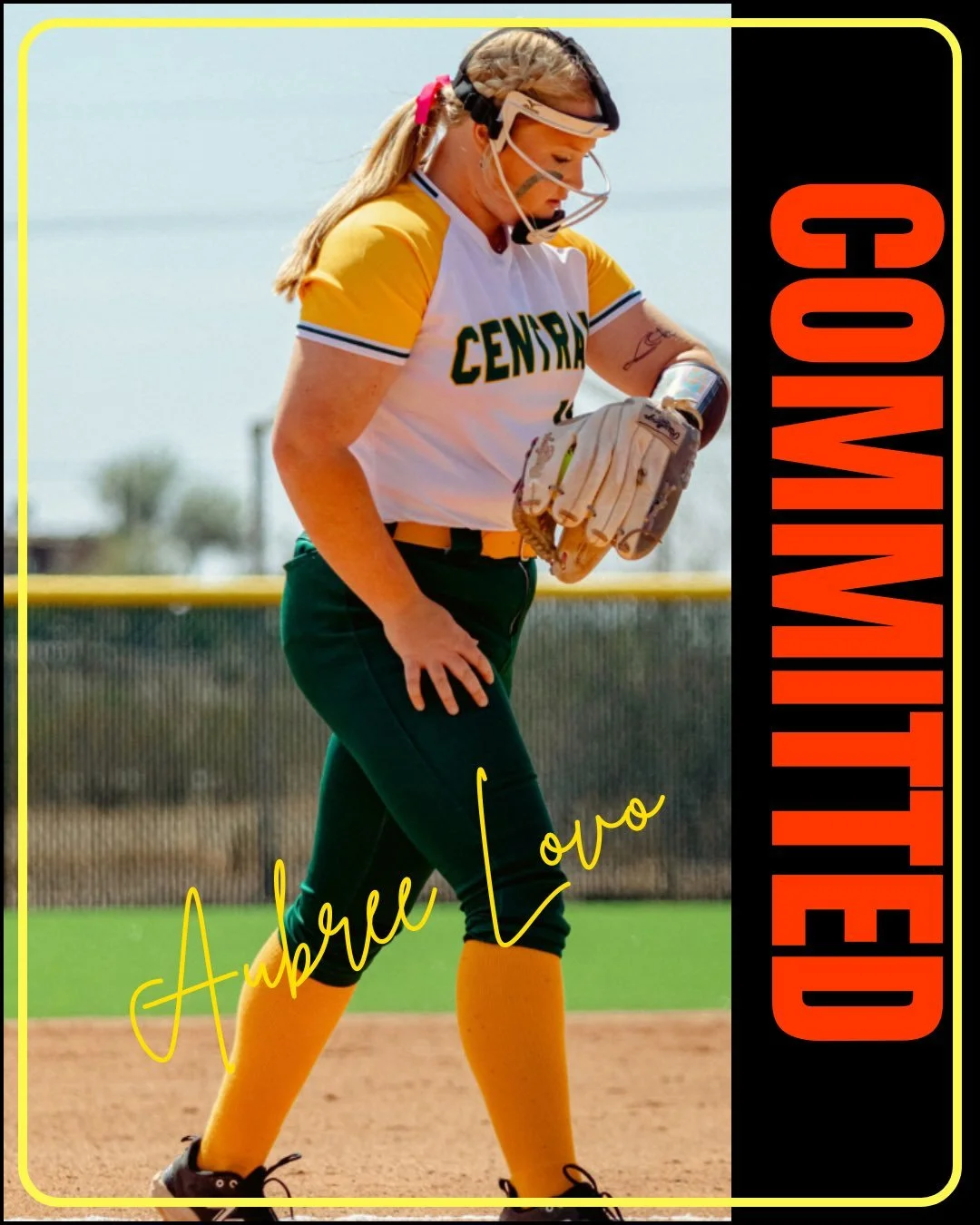 A female baseball player wearing a yellow and white jersey, green pants, and yellow socks on a baseball field, looking down at her glove.