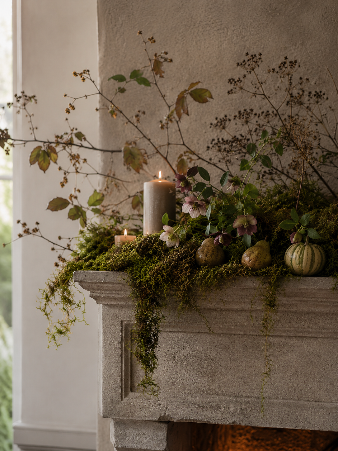 Decorated fireplace mantel with candles, plants, and gourds.