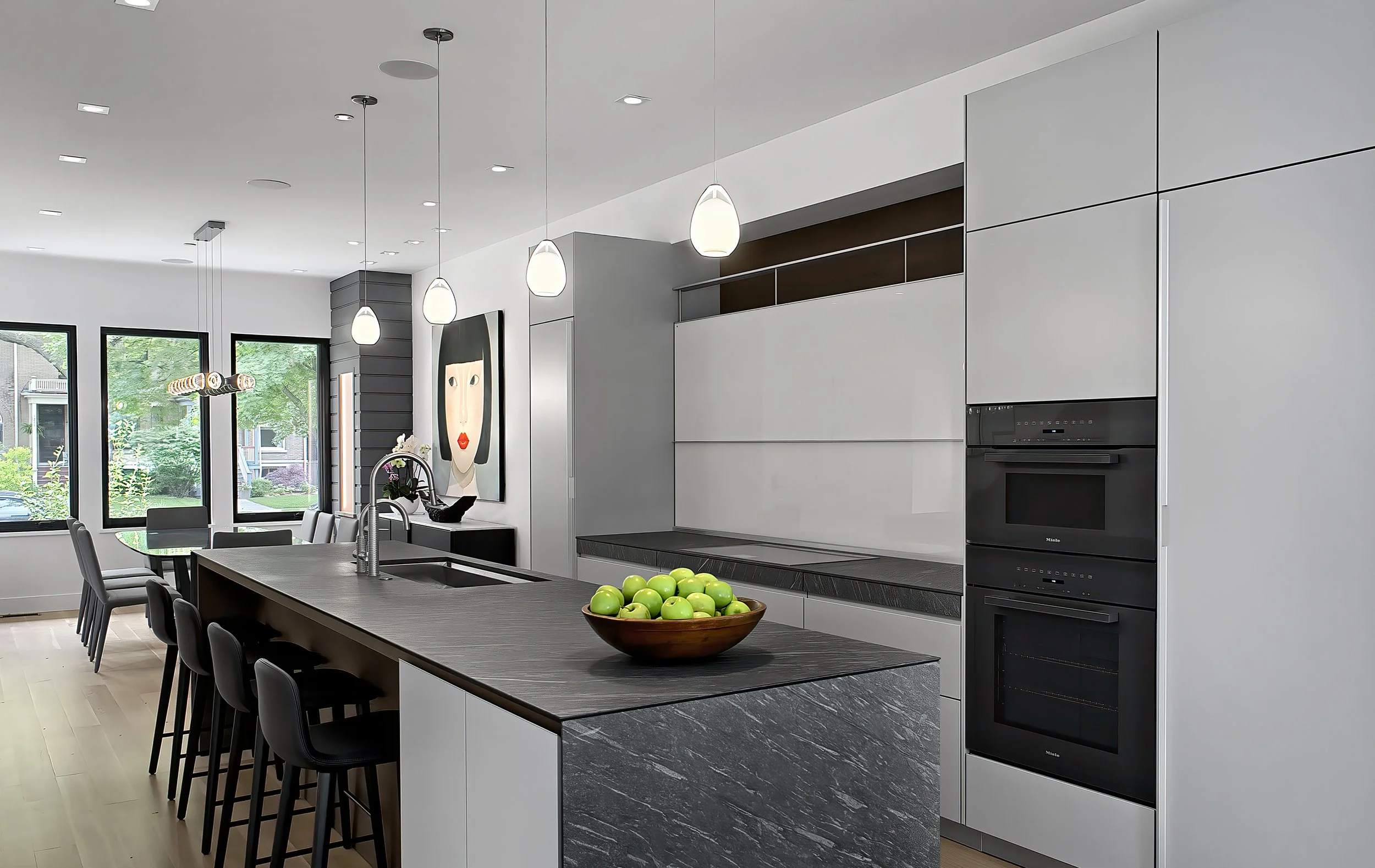 A modern kitchen and dining area with gray appliances and walls and sustainable finishes.