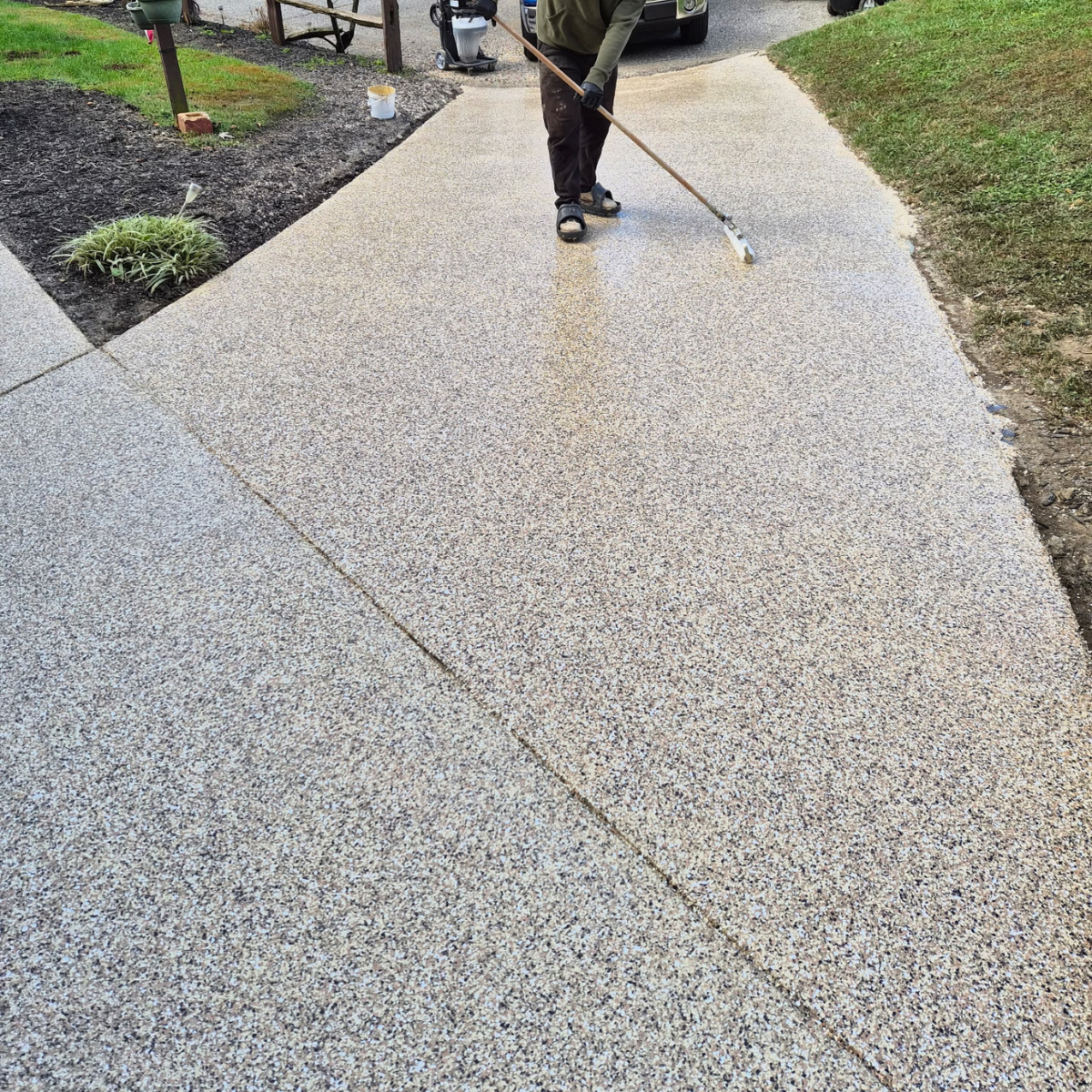 Person power washing a concrete sidewalk in a residential area during daytime.