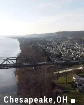 View of Chesapeake, Ohio, showing a river, a bridge, and residential area on the hillside.