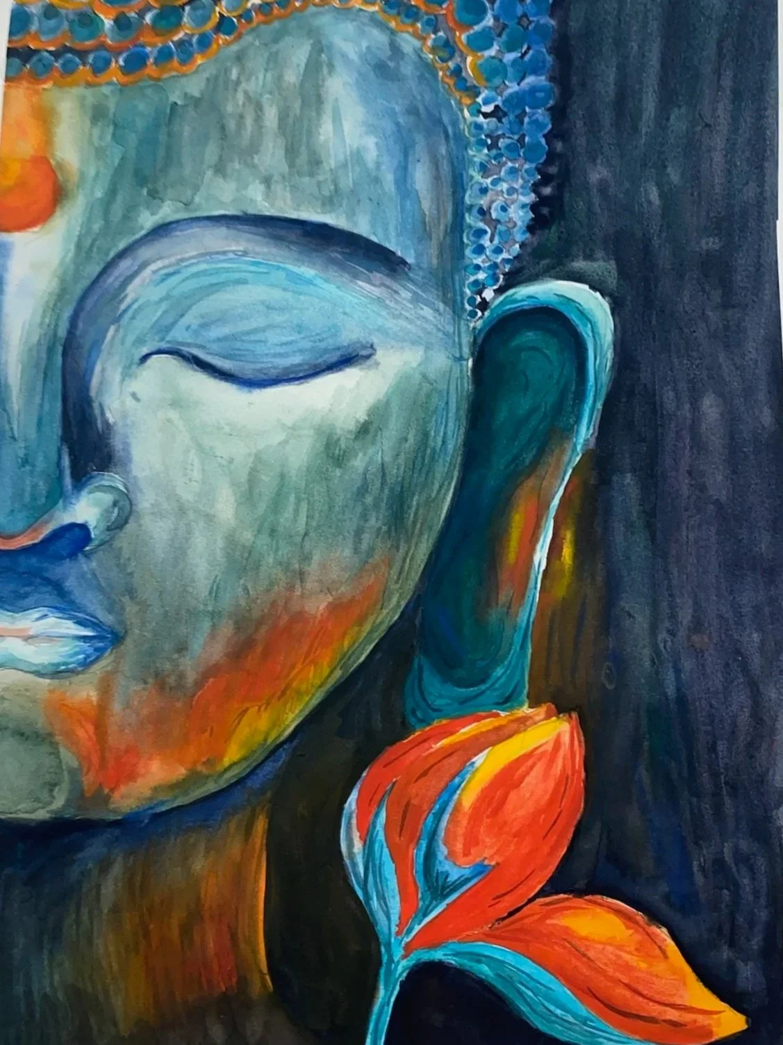 Close-up of a colorful painting of a Buddha's face with half-closed eyes, an elongated earlobe, and bright orange and red leaves at the bottom.