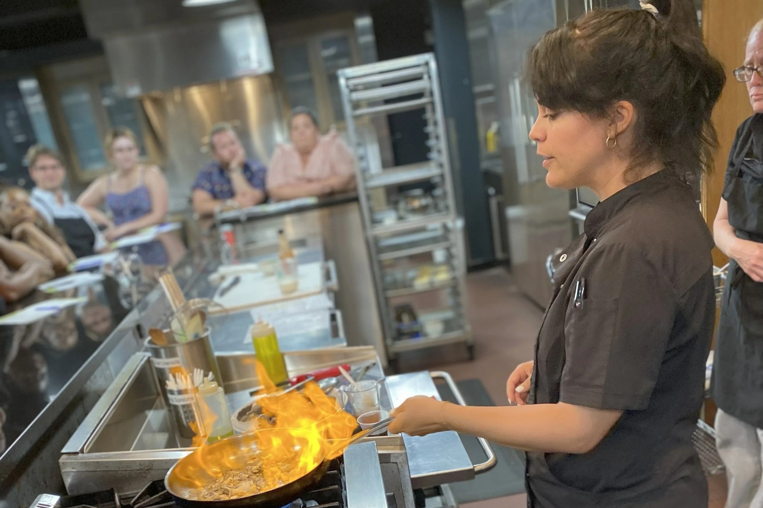 Chef Daniela leading a live cooking class in Metro Detroit kitchen with guests watching and learning