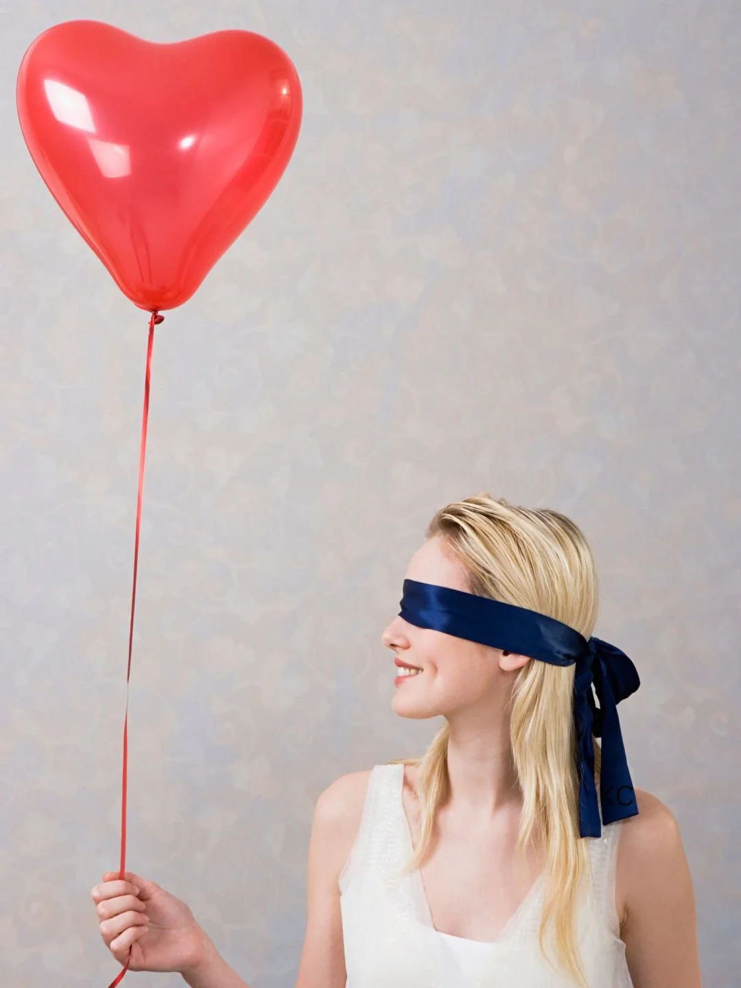 Blindfolded woman holding a valentine's day balloon 