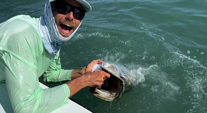 Charlie Tindall  holding a massive tarpon at the side of the boat in the Florida Keys before a safe release.