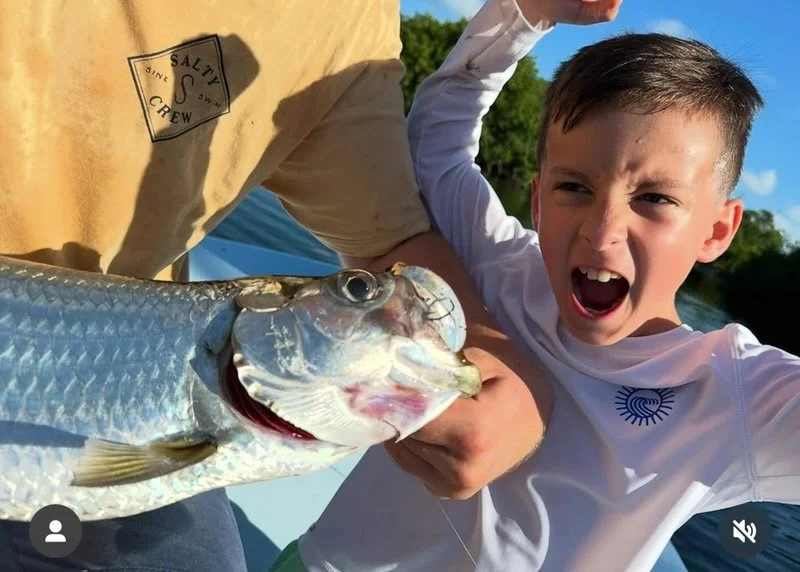 Excited young angler celebrates after landing a juvenile tarpon in the Florida Keys backcountry. Islamorada tarpon fishing is a thrilling experience for families and kids.