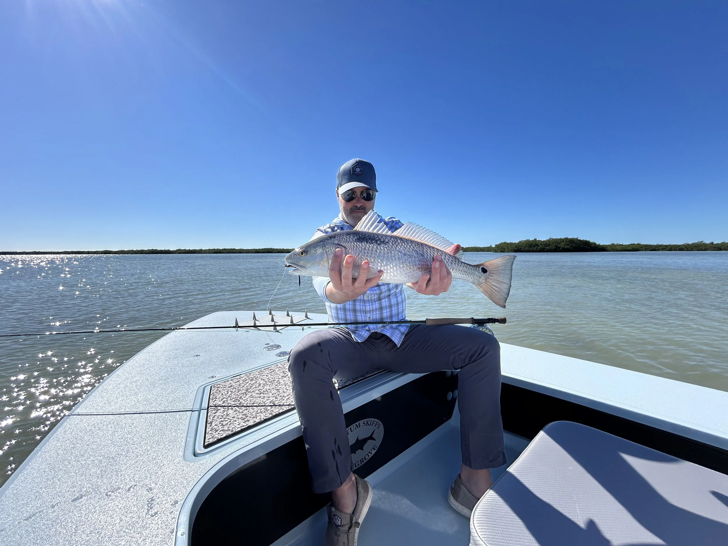Fly fishing in the Florida Keys backcountry near Islamorada, as an angler proudly holds a redfish or red drum caught on the flats—an authentic saltwater flyfishing guide adventure in pristine waters of the everglades.