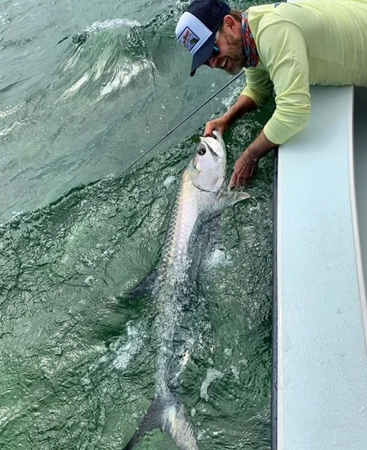 “Fisherman releasing a silver tarpon in the ocean while saltwater fishing in the Florida Keys.”