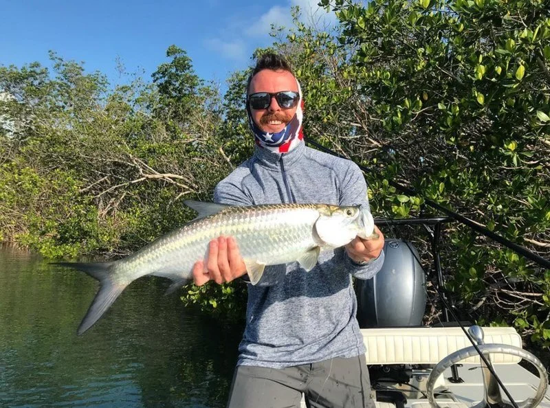 Angler holding a juvenile tarpon caught on light tackle in the Florida Keys backcountry. Islamorada tarpon fishing offers year-round opportunities to chase the “silver king” on fly and spin gear.