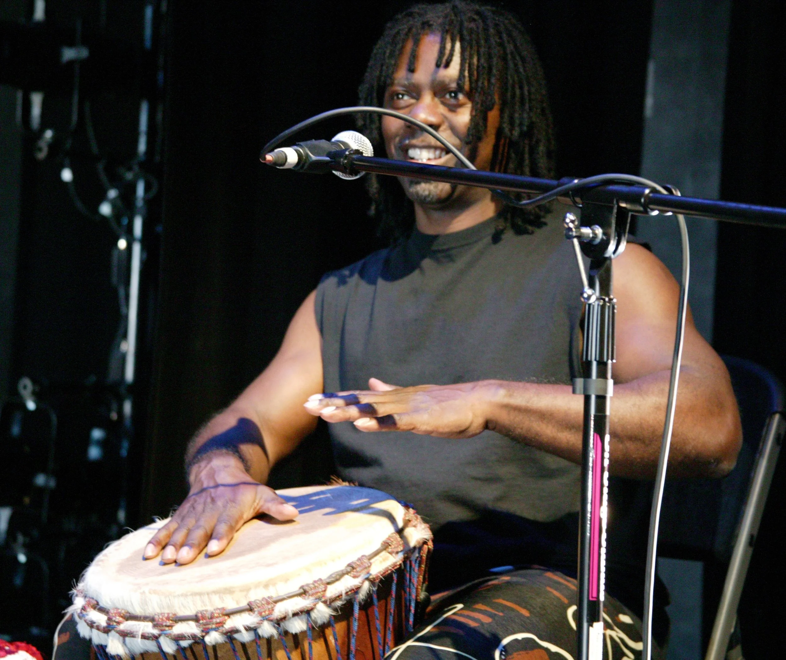 Person playing a drum and singing into a microphone during a performance.