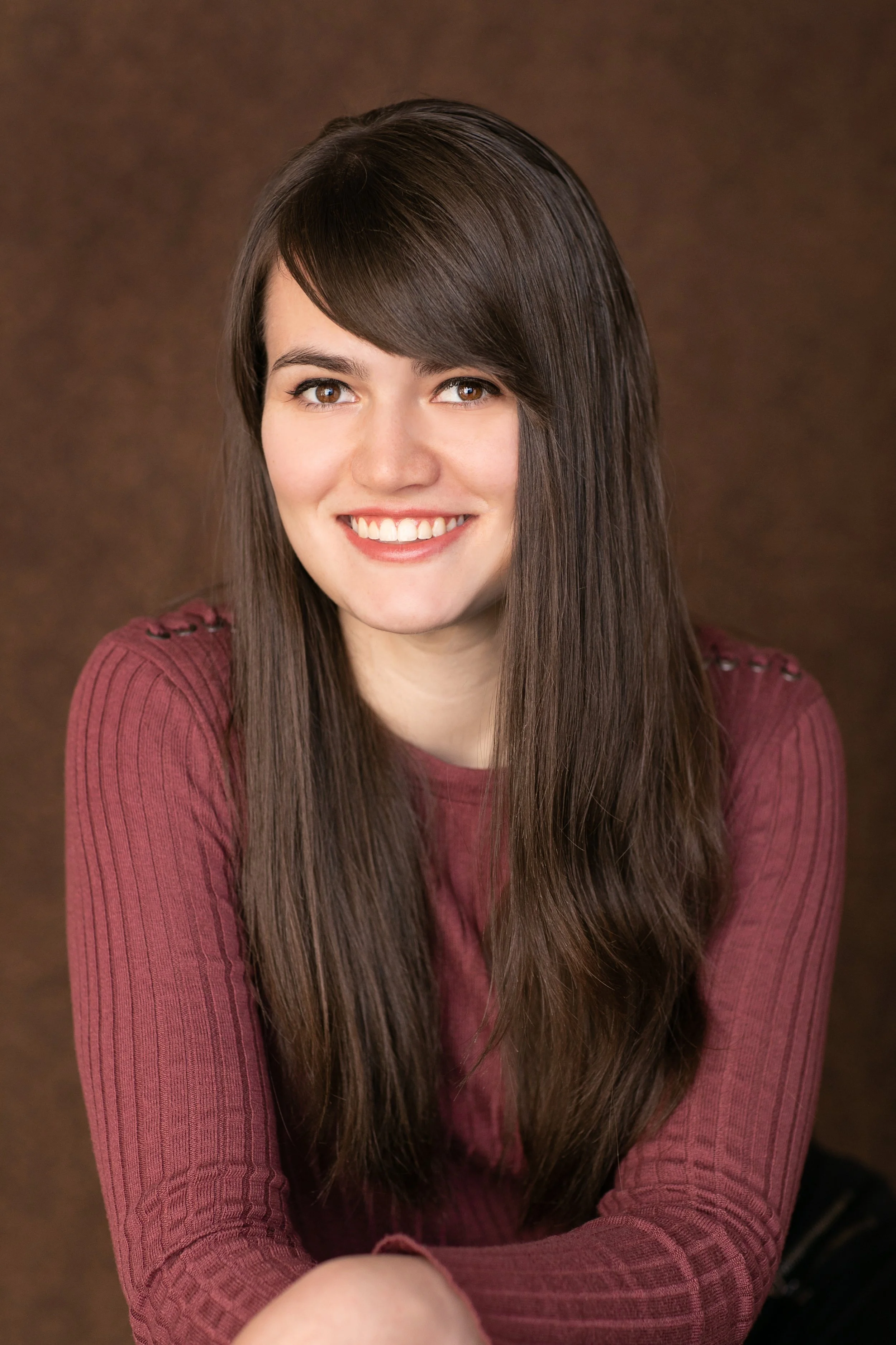 Woman Smiling, with long hair and a maroon long sleeve shirt
