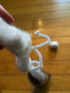 Close-up of a white and orange cat with a fluffy tail standing on a wooden floor, facing away from the camera.